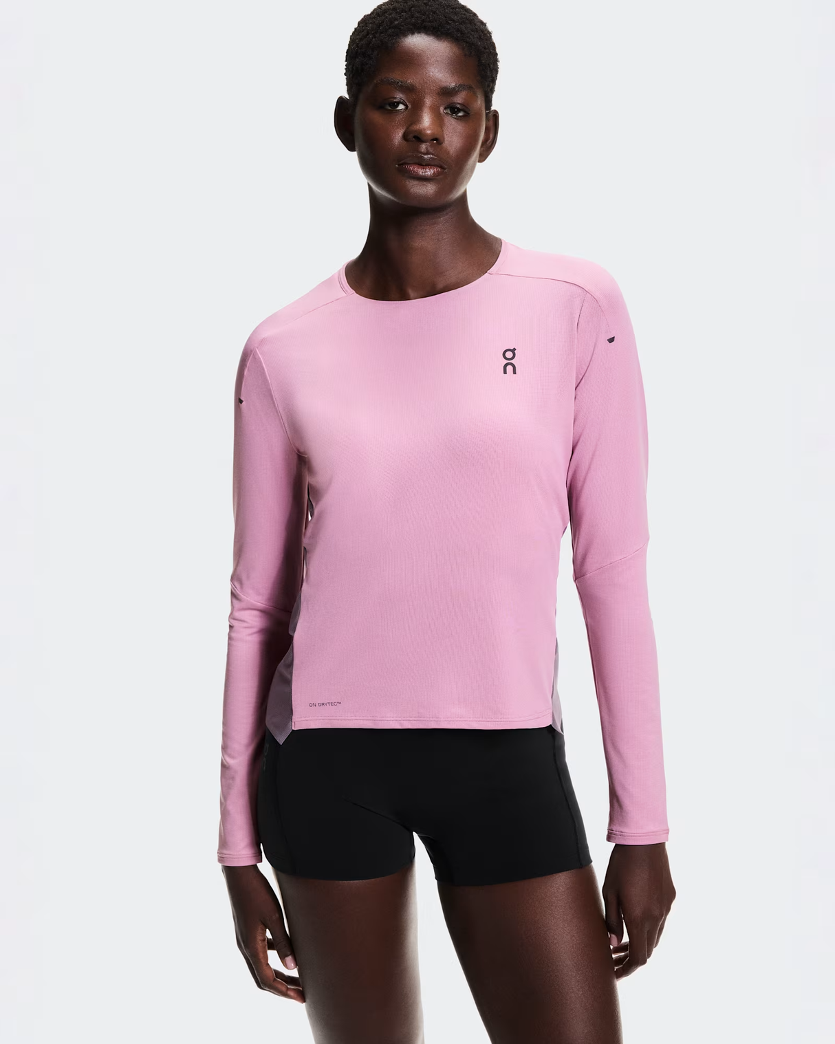 Person wearing a pink long-sleeve athletic shirt and black shorts on a white background - On Performance Long-T (Women's) - Dewberry/Sakura