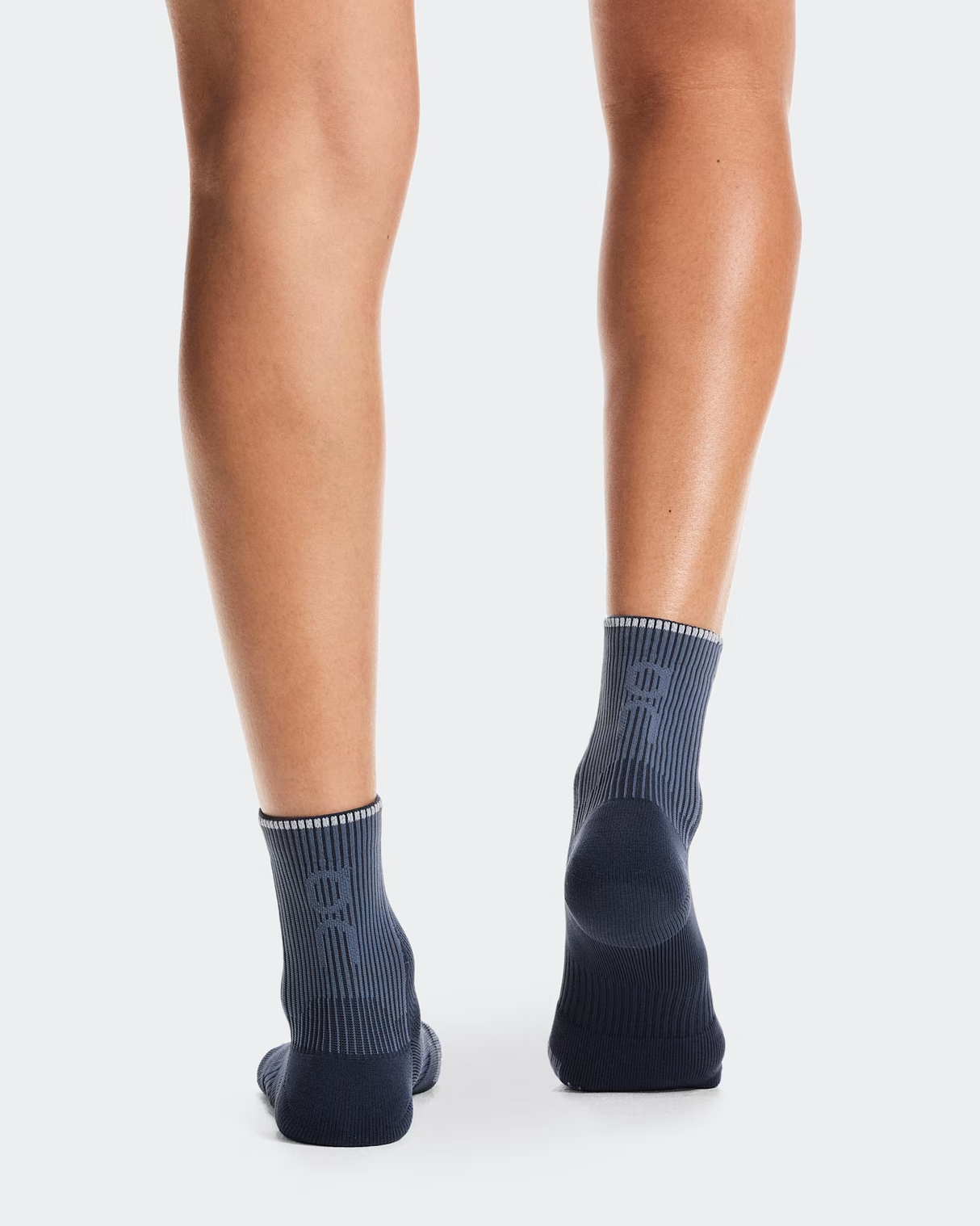 Person wearing dark gray ankle socks on a white background - On Performance Run Sock Mid (Unisex) - Navy/Navy