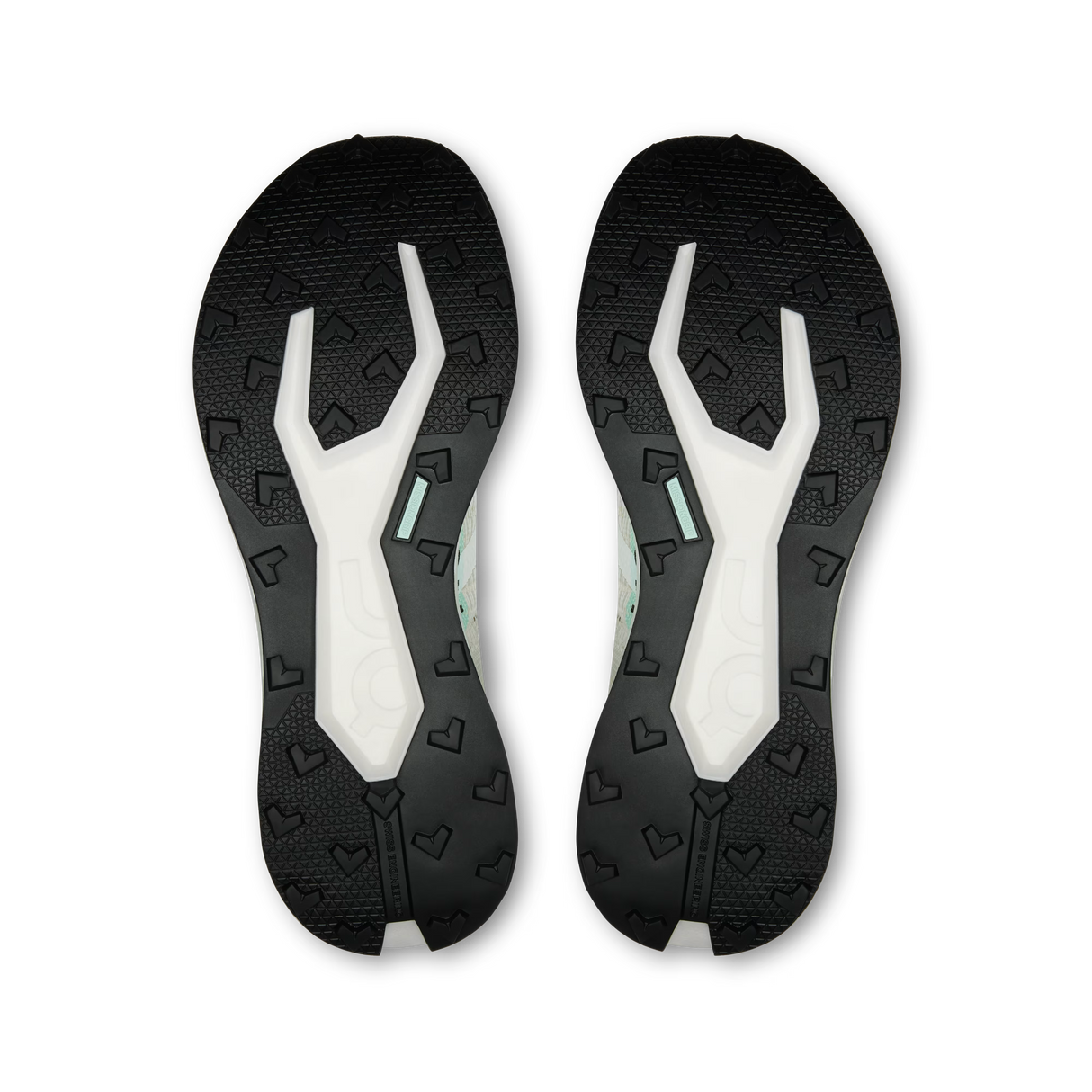 A pair of athletic shoe soles shown from the bottom, featuring a black textured tread with embossed heart-like patterns and a white central channel with a small mint green accent. - On Cloudultra Pro Shoes (Women's) - Ivory/Celeste