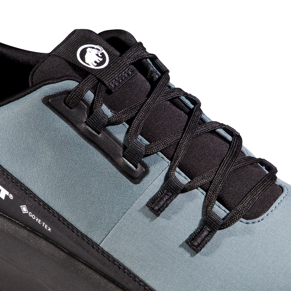Close-up of a trail running shoe showing the side profile, featuring a slate blue-gray upper, black laces, black plastic lace guard, and a black heel section with a visible GORE-TEX logo. - Mammut Aenergy Hike Low GORE-TEX (Men's) - Strata/Black