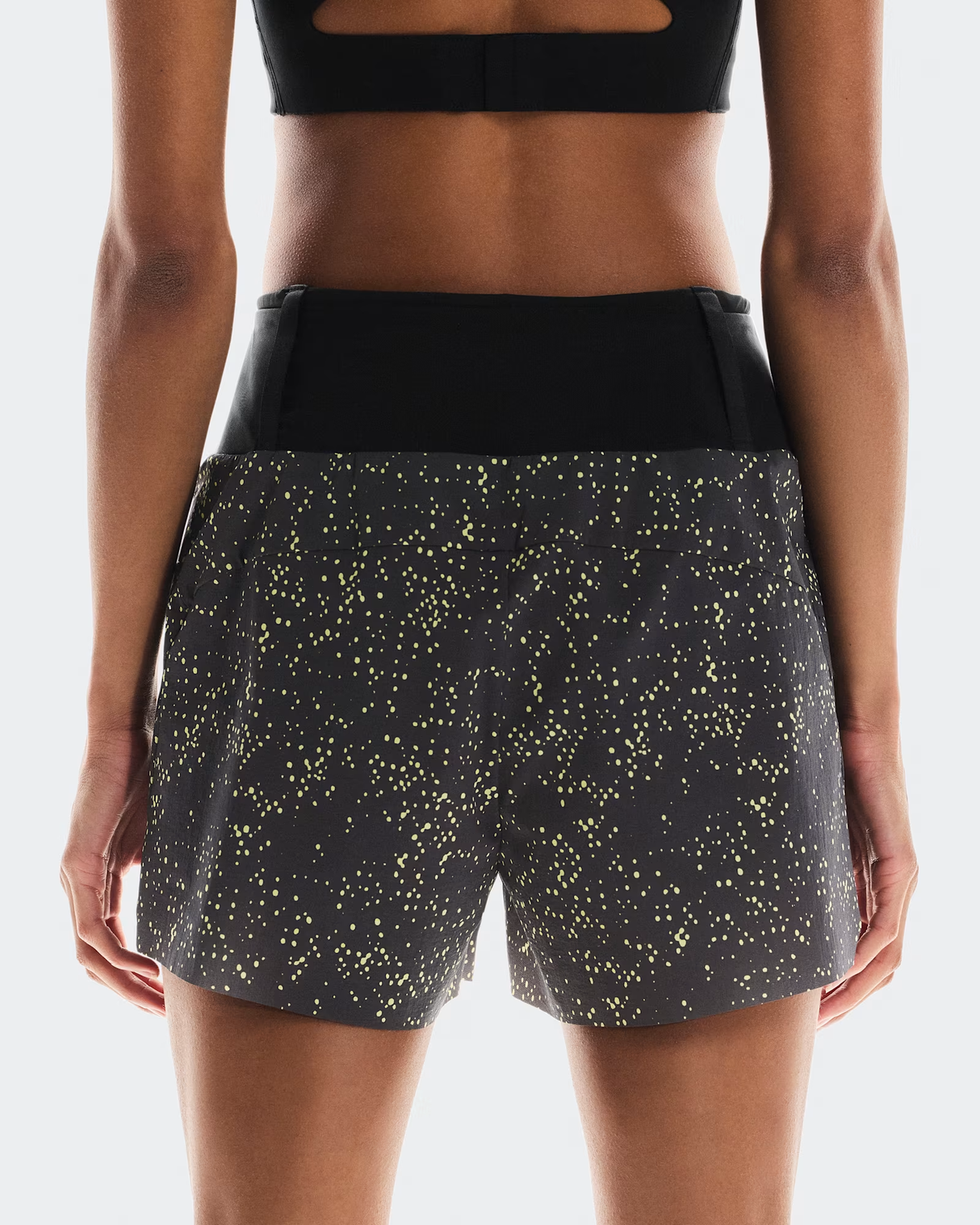 Black athletic shorts with yellow speckle pattern worn by a person on a white background - On Ultra Shorts (Women's) - Iron/Lime