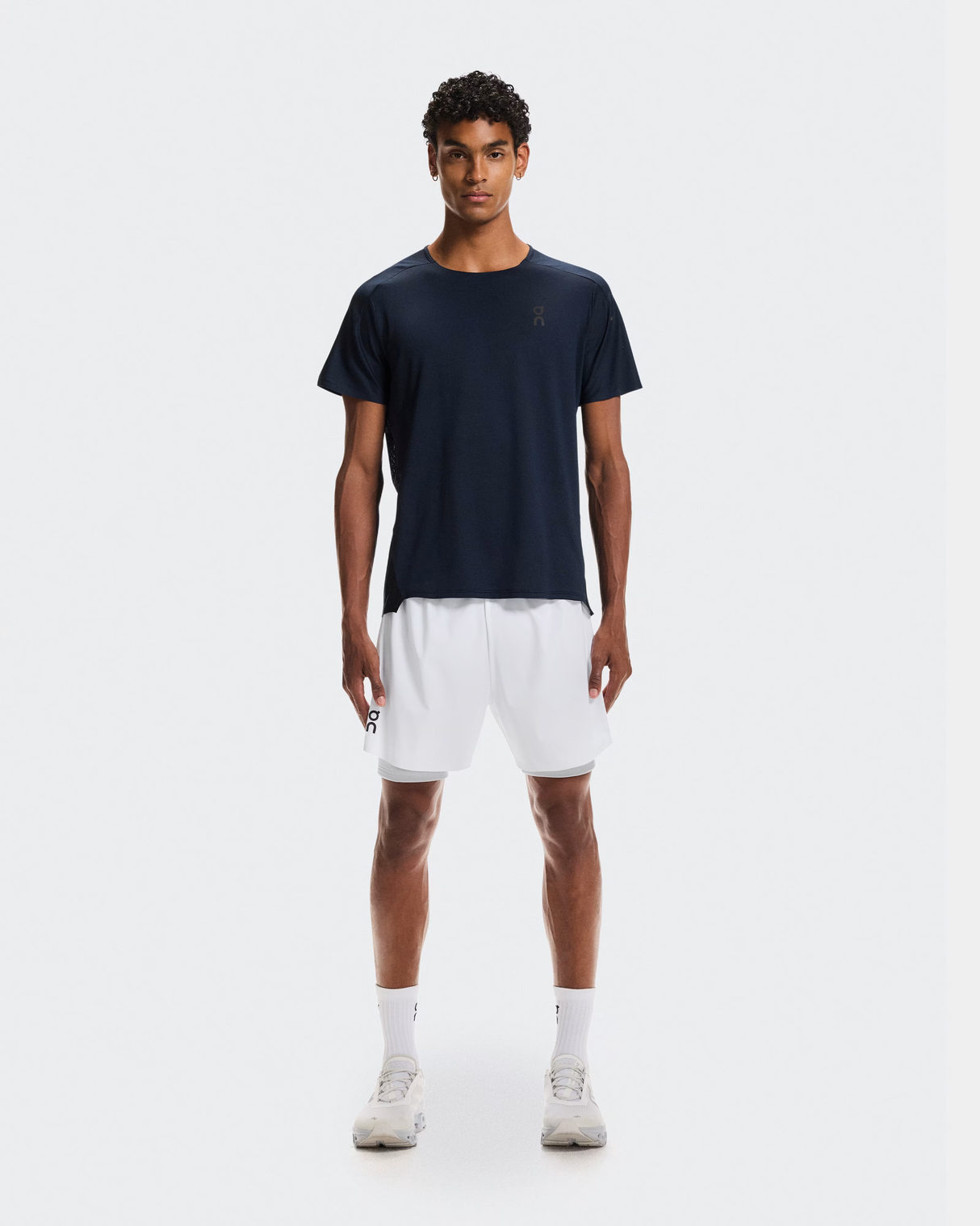 Man wearing a navy t-shirt and white shorts on a white background - On Performance-T (Men's) - Navy/Black