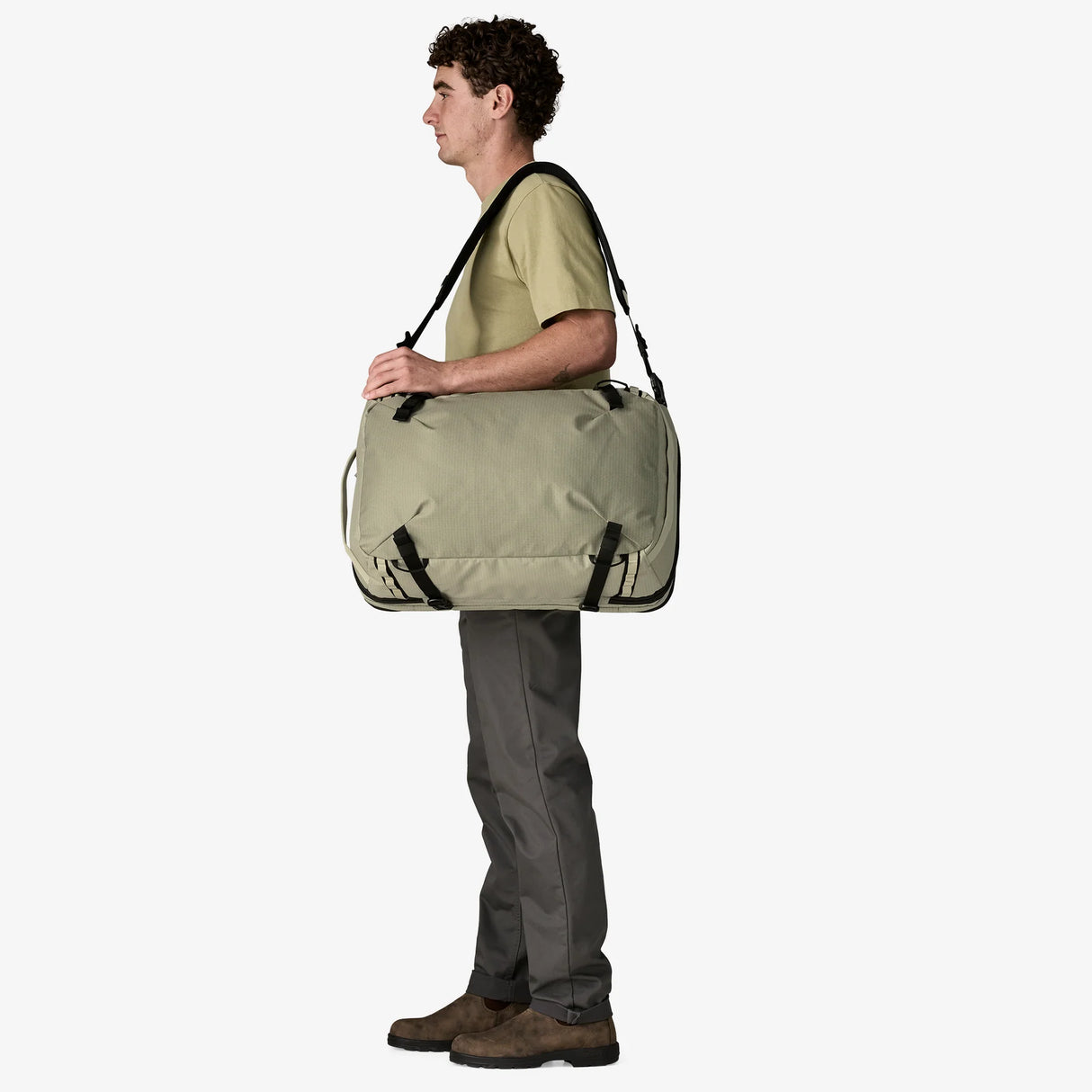 Person carrying a large green duffel bag on a white background - Patagonia Black Hole MLC Pack 45L - Weathered Stone