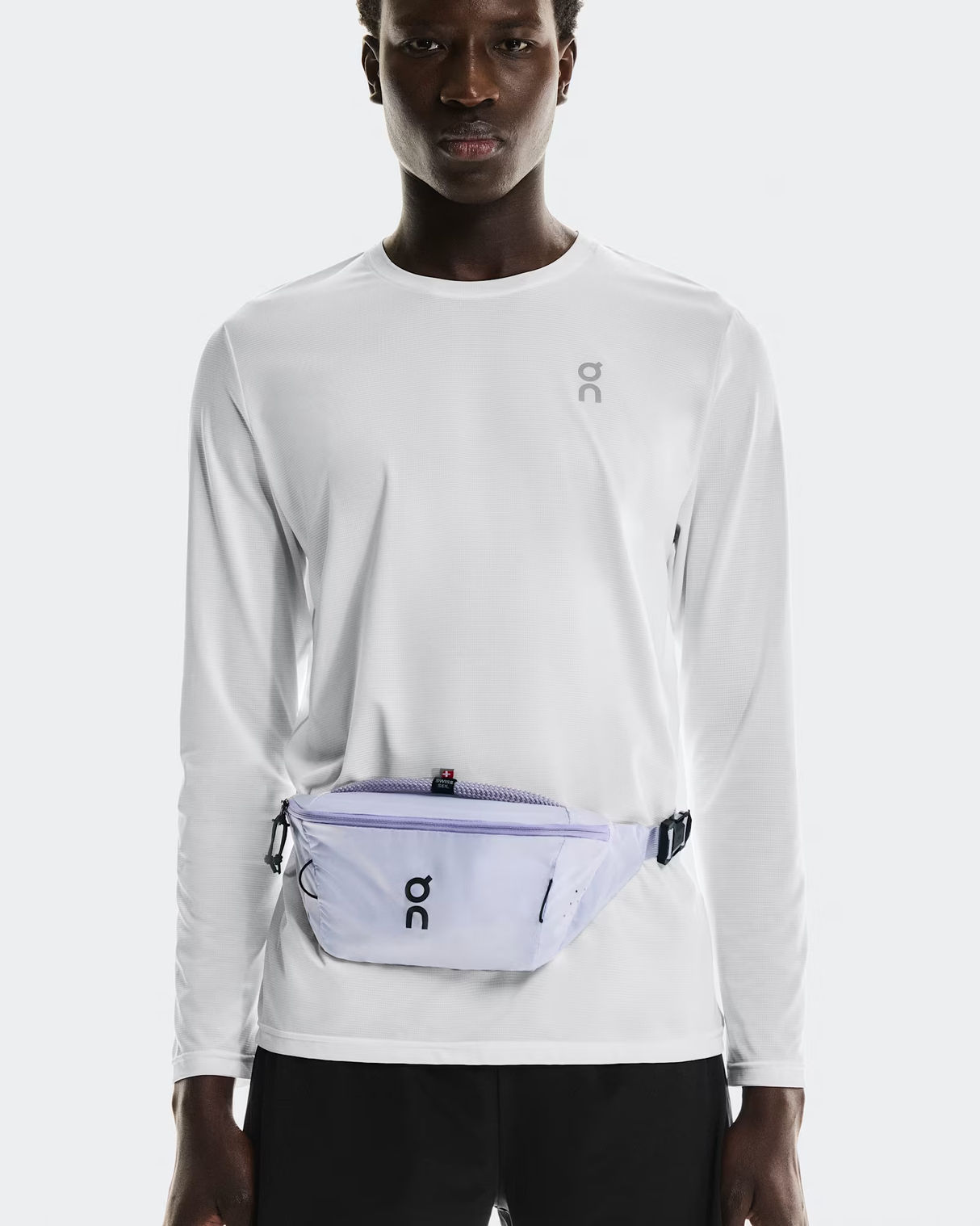Person wearing a white long-sleeve shirt with a purple waist bag on a light gray background - On Waist Pack 2L Lite - Thistle