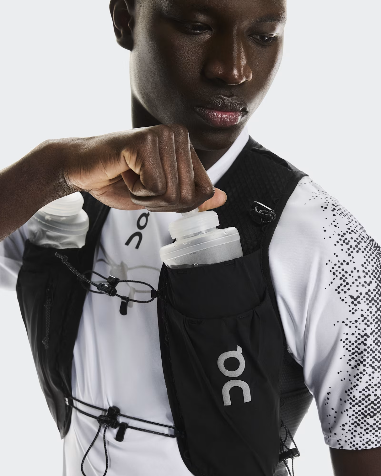 Person wearing a black On running vest with a white shirt underneath on a light gray background - On Ultra Vest Pro (Unisex) - Black