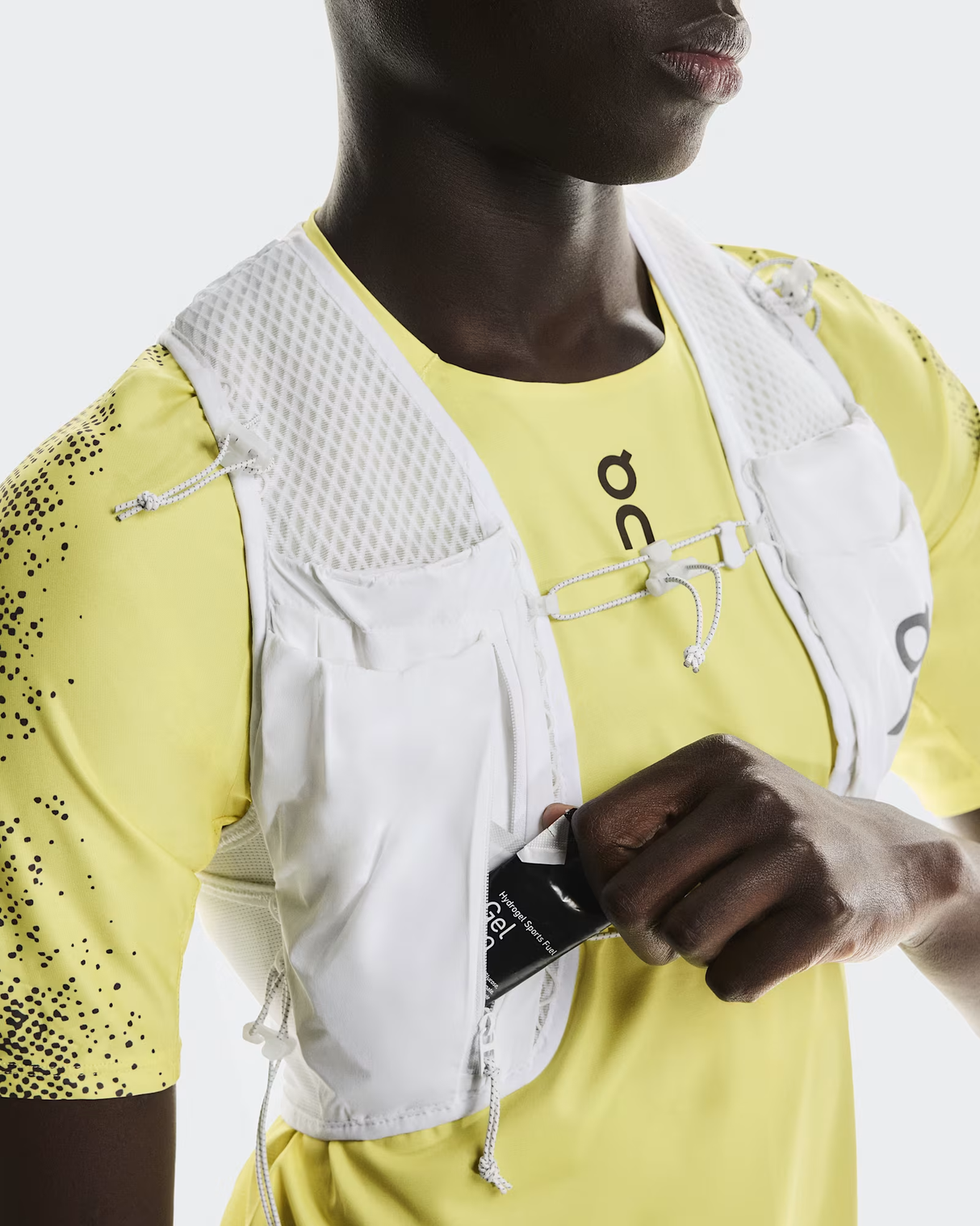 Person wearing a yellow athletic outfit with a white vest, holding a black pouch. - On Ultra Vest Pro (Unisex) - White