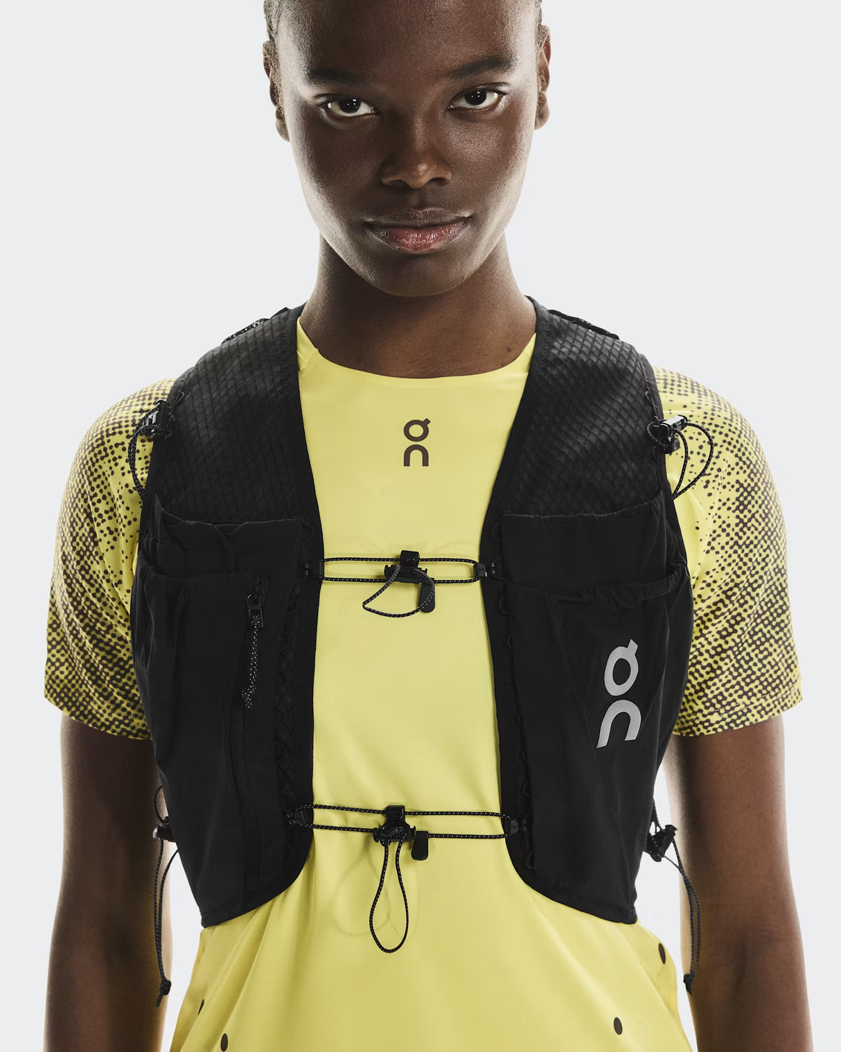 Person wearing a black running vest and yellow athletic shirt on a white background - On Ultra Vest Pro (Unisex) - Black
