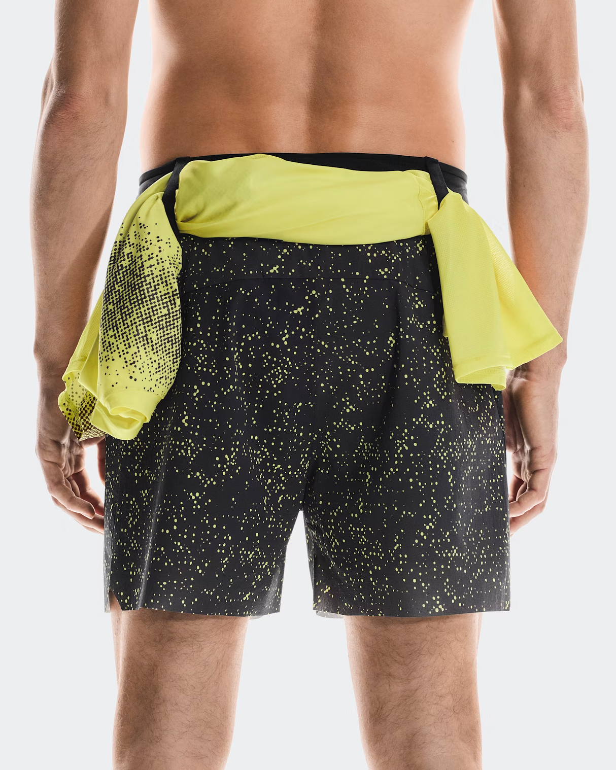 Person wearing black shorts with yellow speckles and a yellow shirt over the shorts on a white - On Ultra Shorts (Men's) - Iron/Limebackground