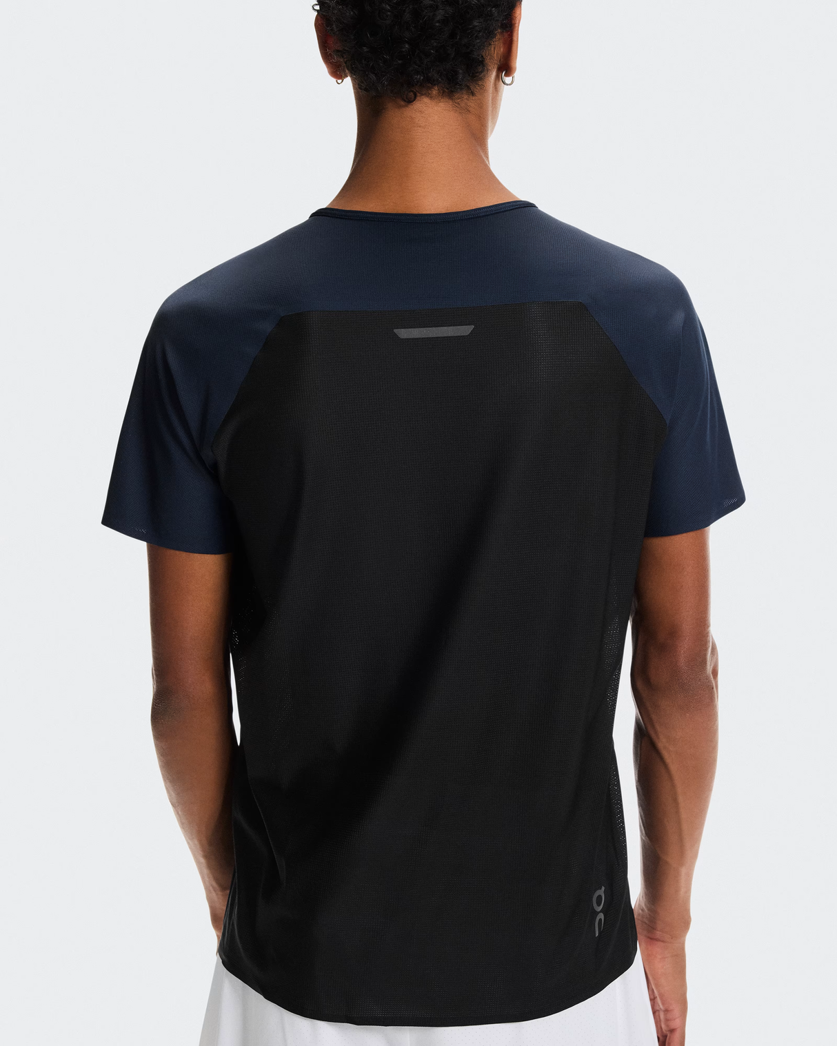 Person wearing a black and navy athletic shirt on a white background - On Performance-T (Men's) - Navy/Black