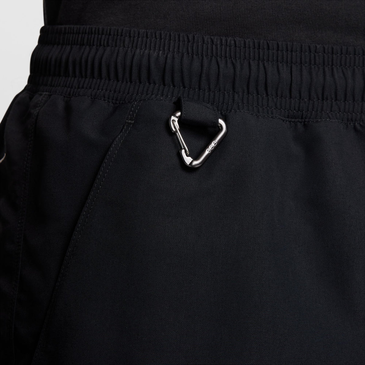 Close-up of black athletic shorts with an elastic waistband and a silver metal carabiner attached near the pocket. - Nike ACG Reservoir Goat Shorts (Men's) - Black/Anthracite/Summit White