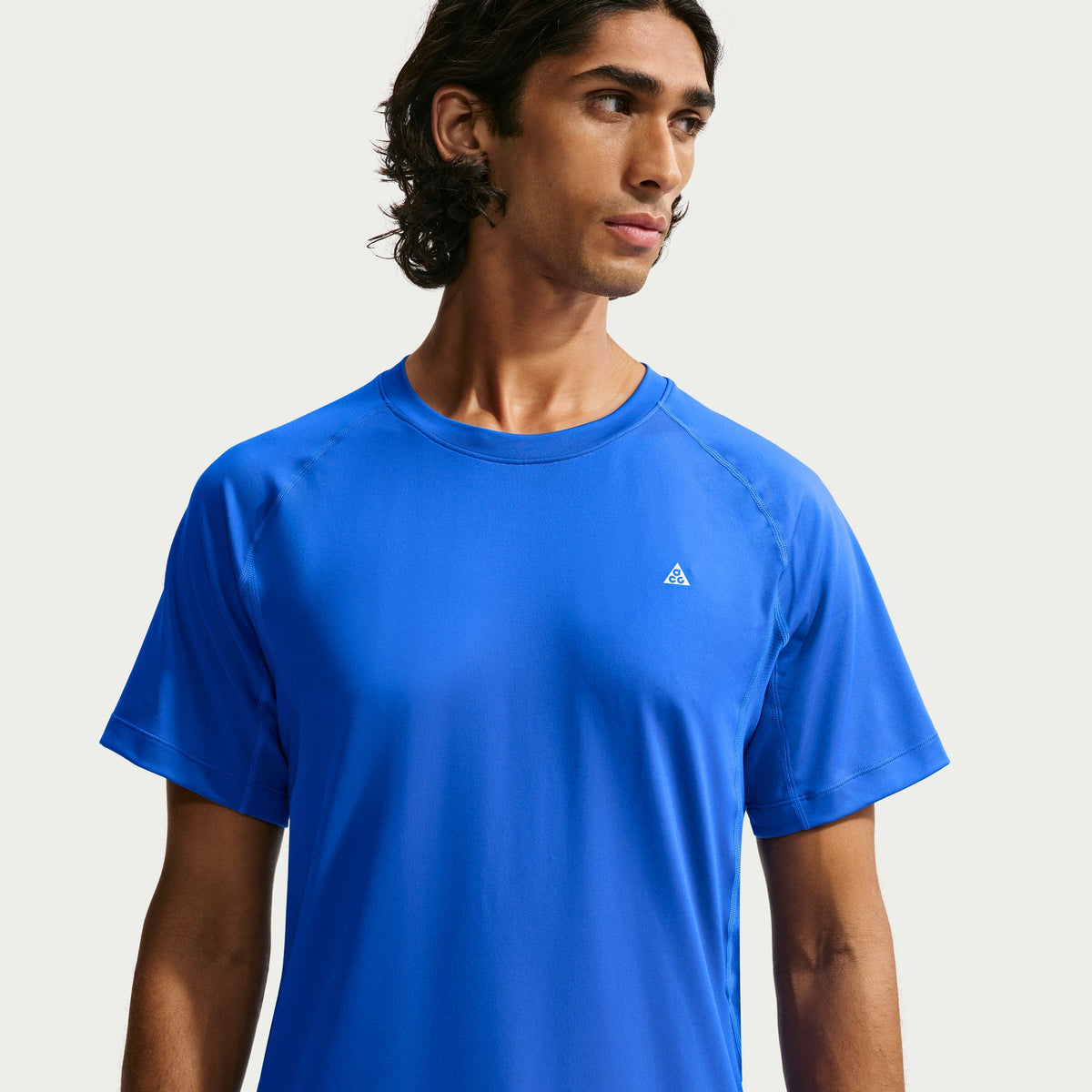A man wearing a bright blue short-sleeve athletic t-shirt with a small white Adidas logo on the left chest, photographed against a light gray studio background. - Nike ACG Dri-FIT Short-Sleeve Base Layer Top (Men's) - Hyper Royal/Summit White