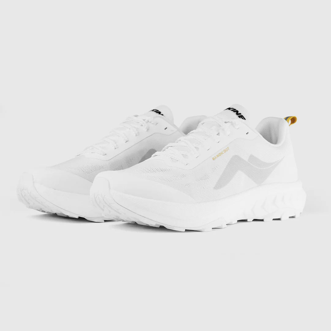 A pair of white athletic sneakers with a minimalist design, featuring a light gray wave-like logo on the side and a small gold pull tab on the heel, set against a solid light gray background. - Tarkine Bandicoot Shoes (Women's) - Whiteout