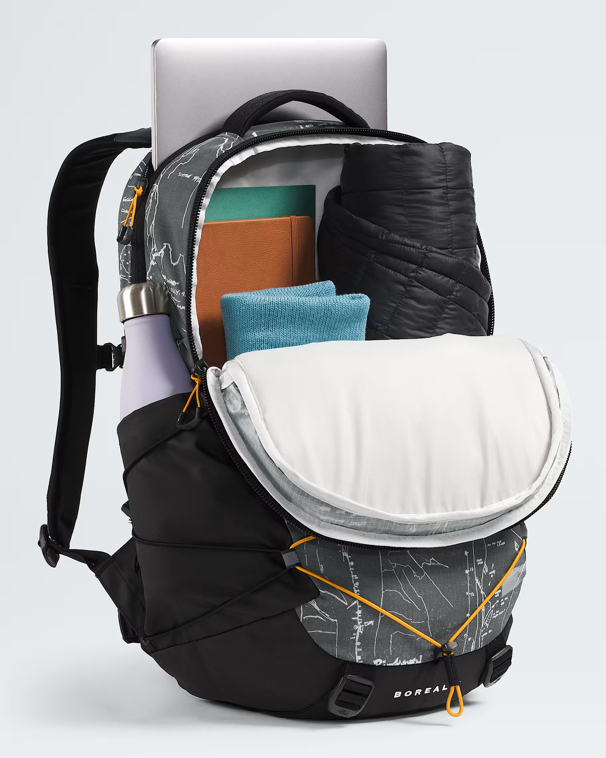 A BOREAL backpack shown open and packed with travel items, including a laptop, folded clothing, and a rolled jacket, on a light gray studio background. - The North Face Borealis Backpack - Anthracite Grey Conrad Topos Print/Summit Gold