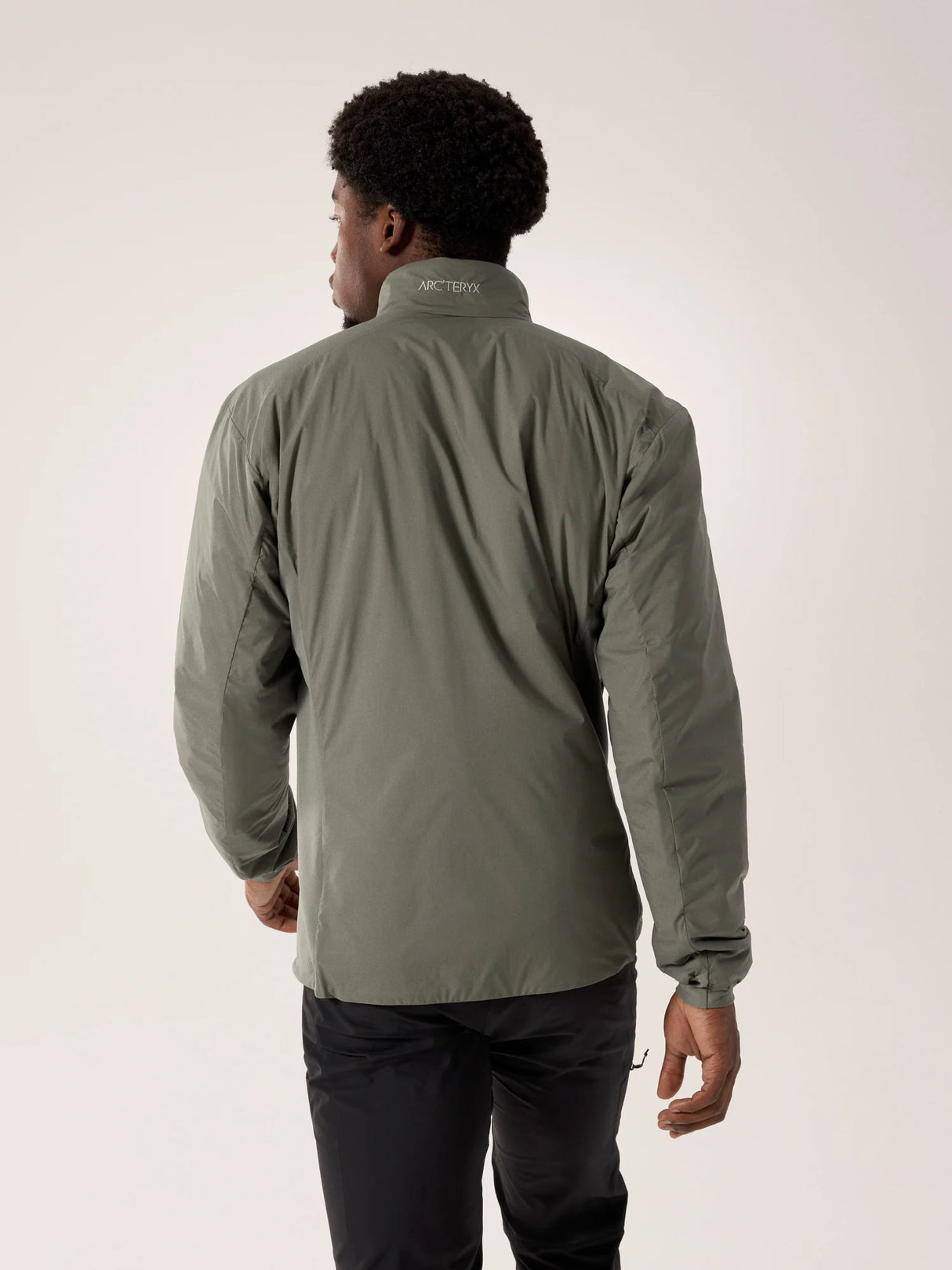 Person wearing a green jacket with a visible brand logo on a light gray background - Arc'teryx Atom Jacket (Men's) - Forage