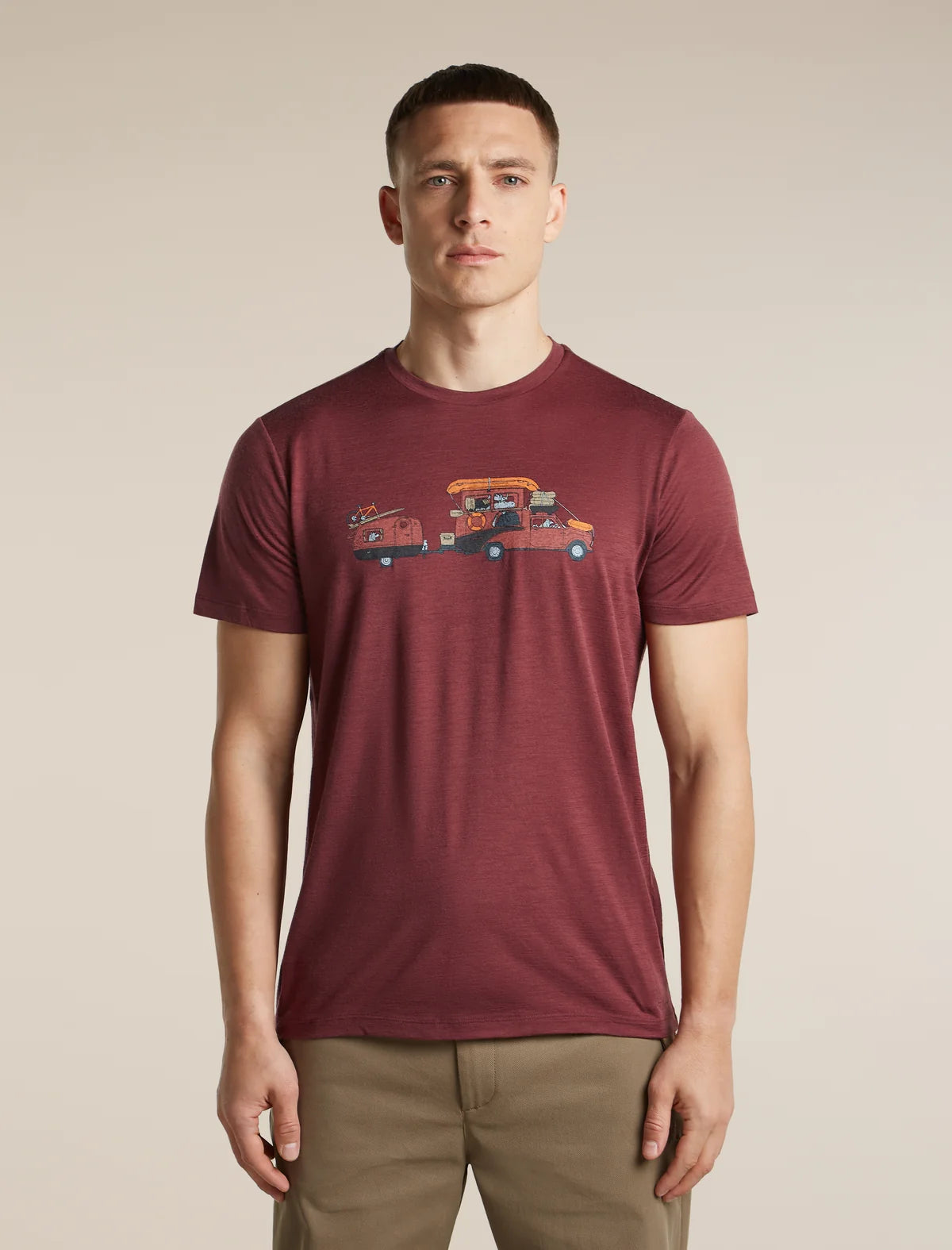 A man wearing a heathered maroon crewneck t-shirt with a graphic of a tow truck carrying a car, paired with khaki pants, against a solid beige background. - Icebreaker Merino 150 Tech Lite Short Sleeve T-Shirt Transportage (Men's) - Port