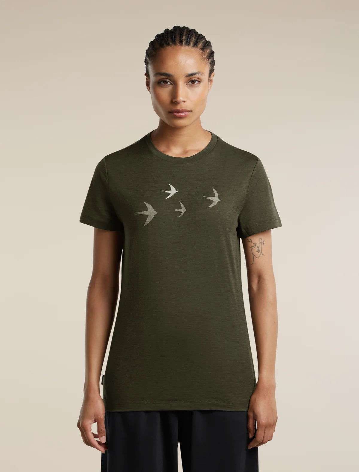 A woman modeling an olive green short-sleeve t-shirt with a graphic of four flying birds in light gray on the chest, set against a plain beige background. - Icebreaker Merino 150 Tech Lite Short Sleeve T-Shirt Bird Transit (Women's) - Dark Loden