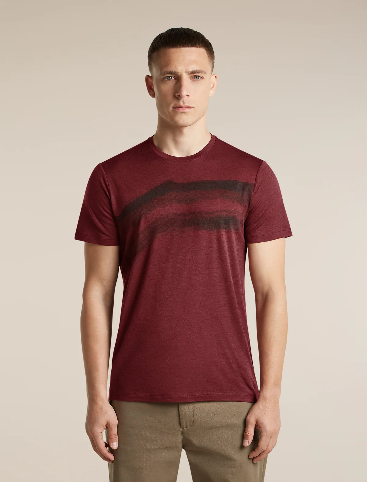 A man wearing a short-sleeve crewneck t-shirt in maroon with a dark horizontal stripe pattern across the chest, paired with khaki pants, against a solid beige background. - Icebreaker Merino 150 Tech Lite Short Sleeve T-Shirt Getaway (Men's) - Port