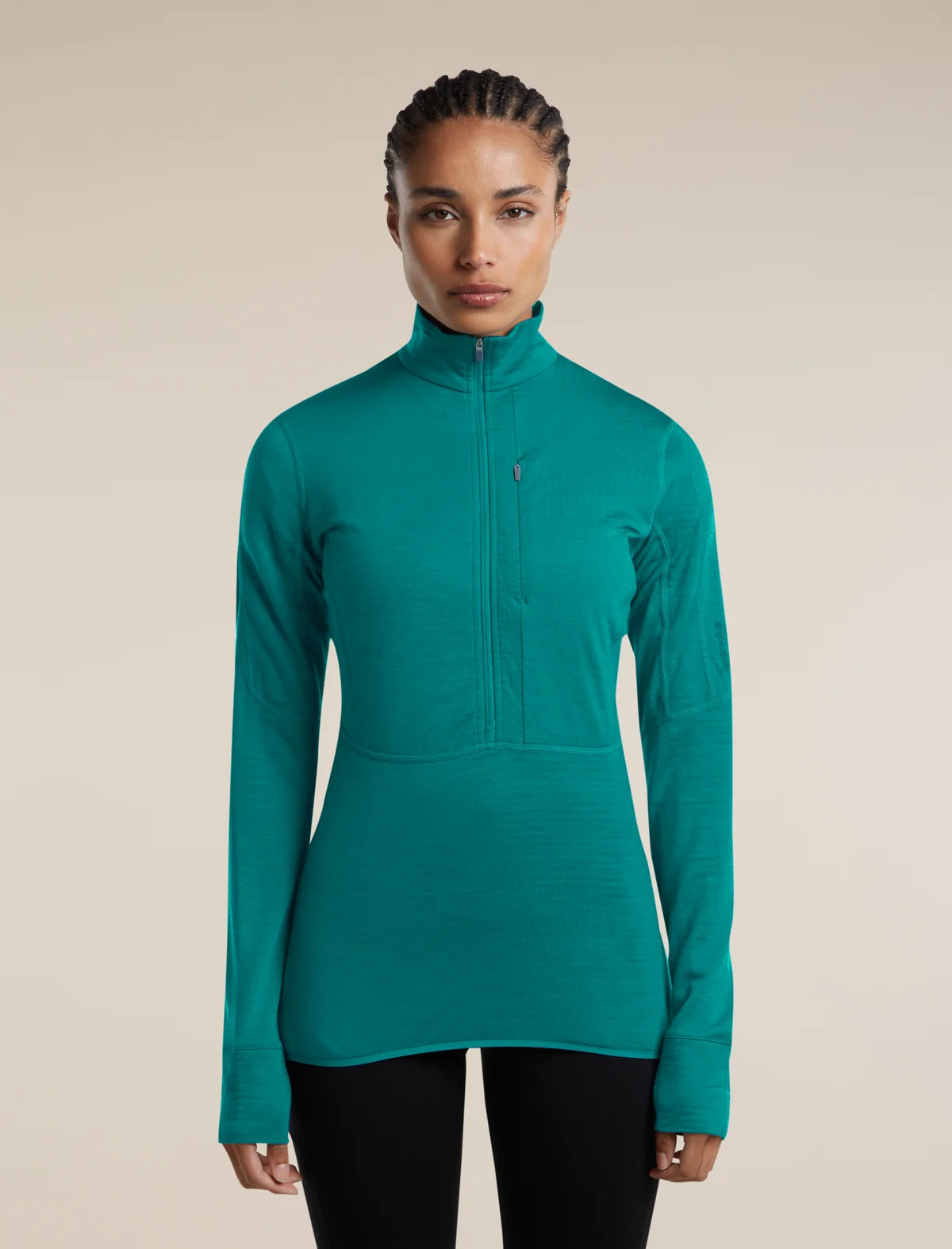 A woman modeling a teal green long-sleeve half-zip athletic top against a solid beige background. - Icebreaker Merino Blend 200 RealFleece Descender Long Sleeve Half Zip (Women's) - Tidal Teal