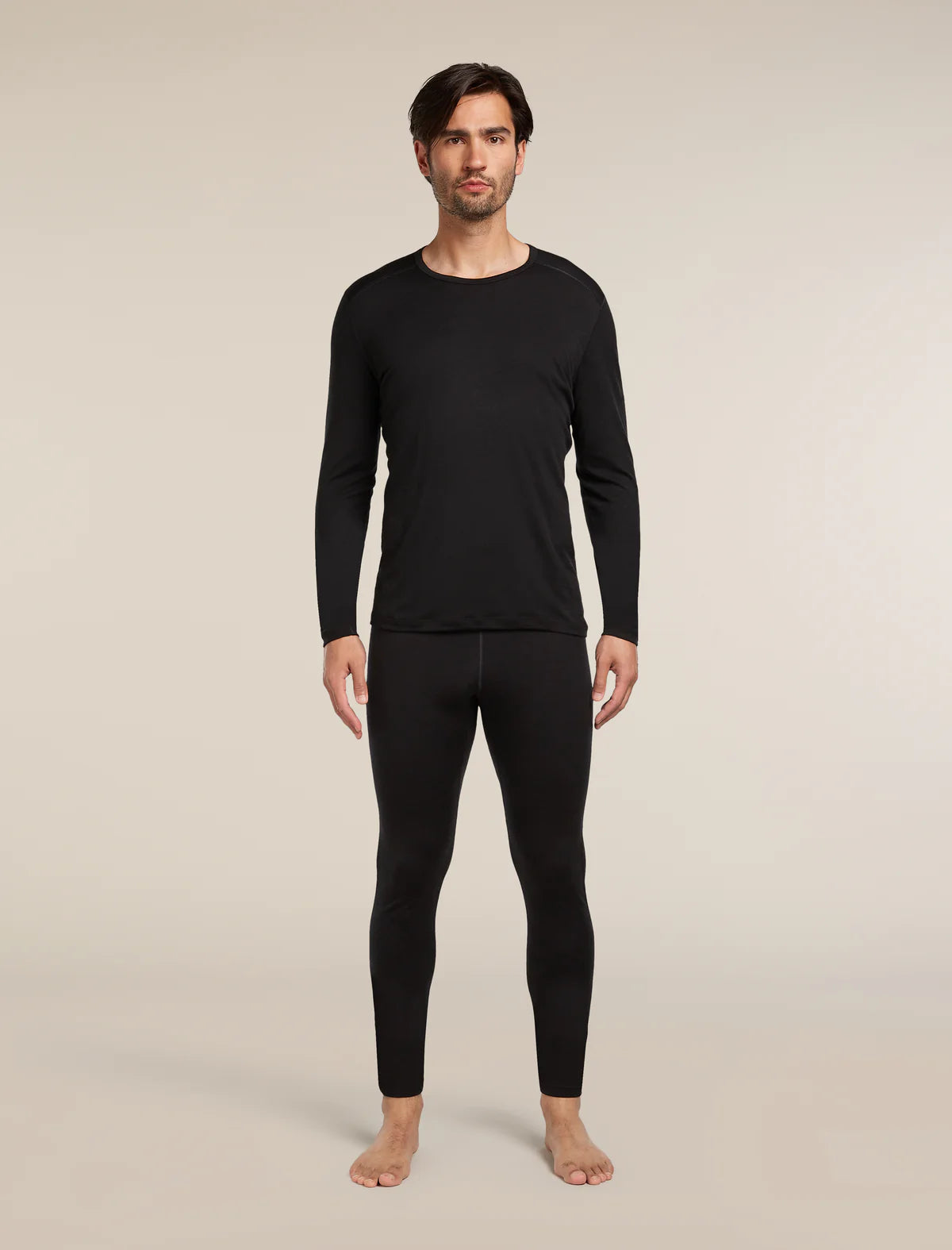 Man wearing black long-sleeve shirt and pants on a beige background - Icebreaker Merino 200 Oasis Thermal Leggings (Men's) - Black