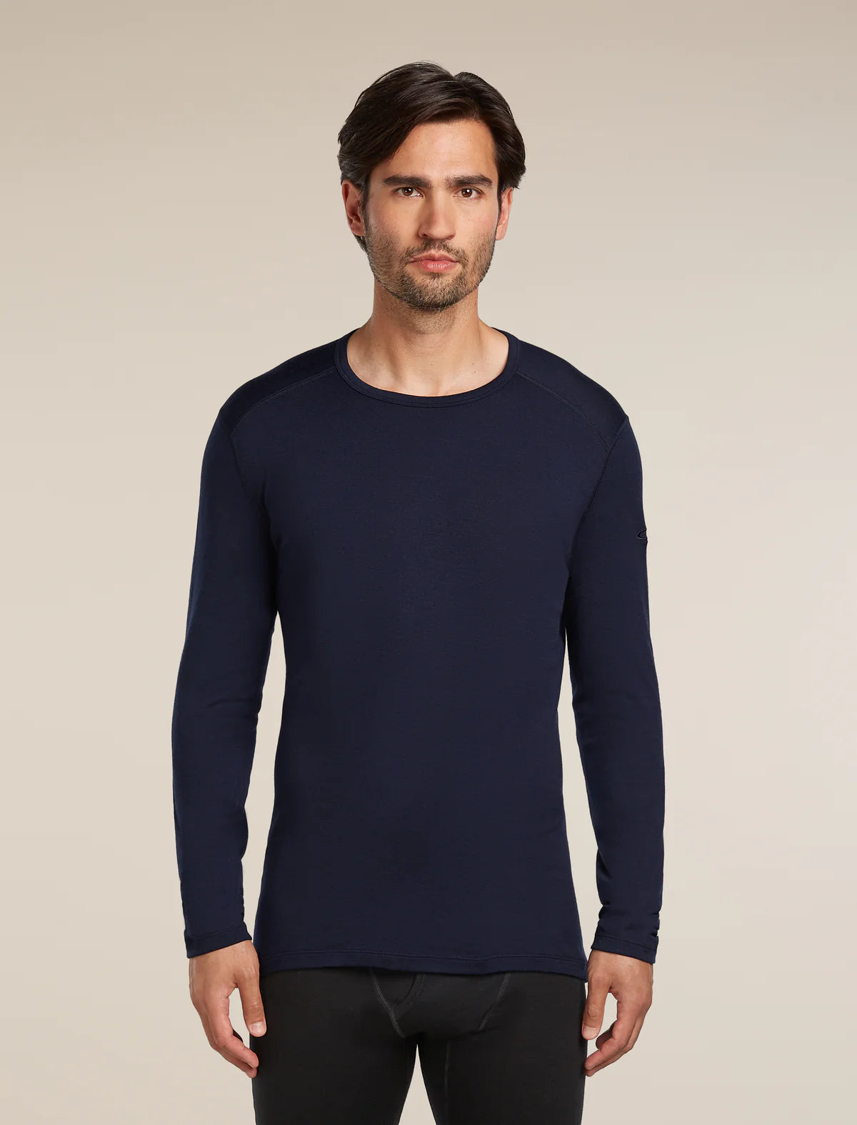 Man wearing a navy long-sleeve shirt against a beige background - Icebreaker Merino 260 Oasis Long Sleeve Crew Thermal Top (Men's) - Midnight Navy