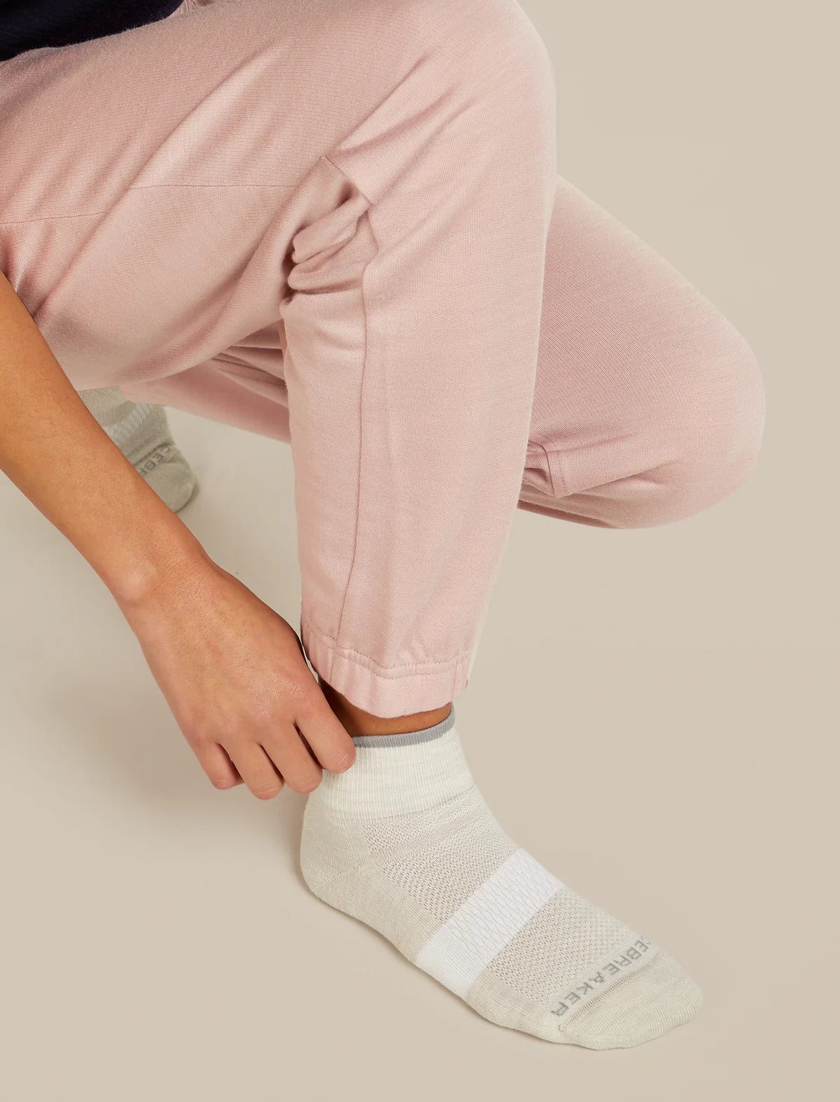 Person wearing light pink pants and white socks on a beige background - Icebreaker Merino Multisport Light Mini Socks (Women's) - Ecru Heather/Alloy