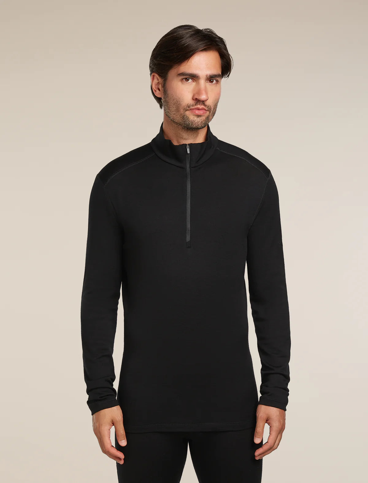 Man wearing a black long-sleeve shirt with a quarter zip on a beige background - Icebreaker Merino 260 Tech Long Sleeve Half Zip (Men's) - Black