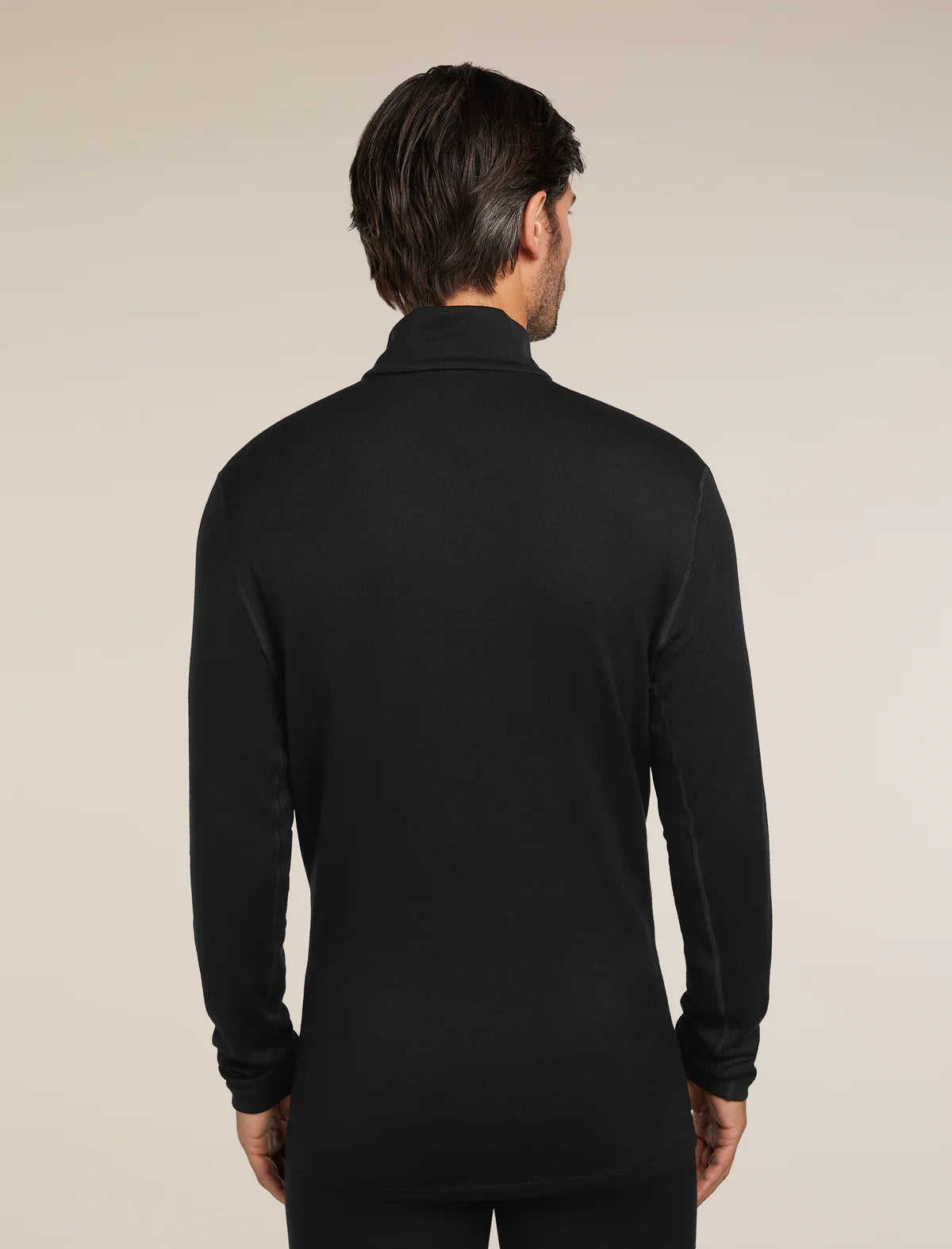 Man wearing a black long-sleeve shirt against a beige background - Icebreaker Merino 260 Tech Long Sleeve Half Zip (Men's) - Black