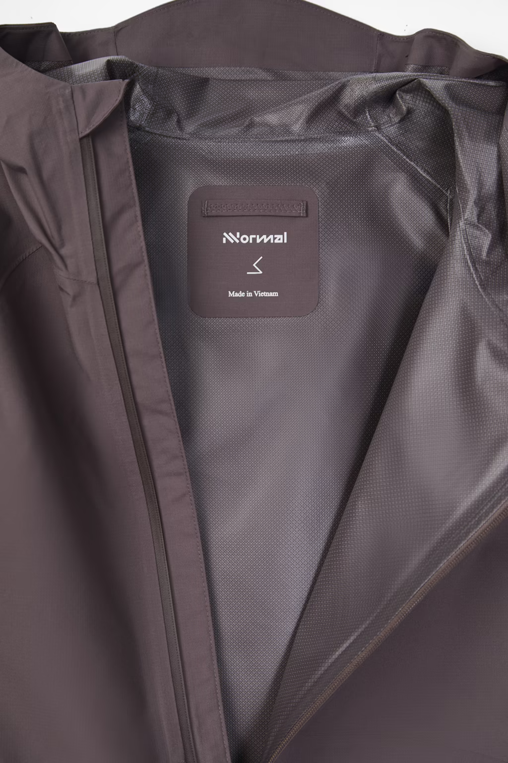 Close-up of the interior collar and lining of a dark brown jacket, showing a sewn-in label that reads 'Normal' and 'Made in Vietnam'. - NNormal Trail Rain Jacket 02 (Men's) - Purple