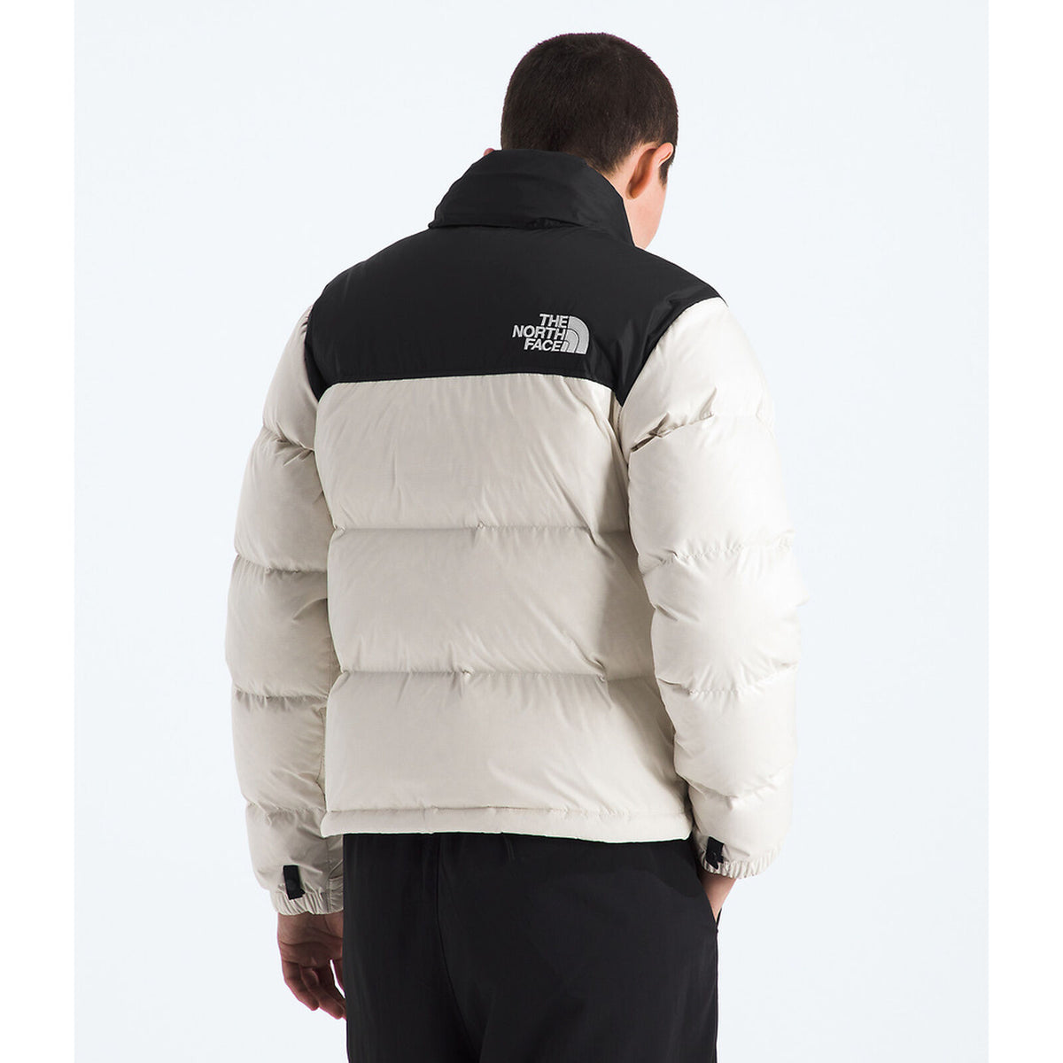 Person wearing a two-tone jacket with black and beige colors on a white background - The North Face 1996 Retro Nuptse Jacket (Womens) - White Dune/TNF Black-Recycled Down