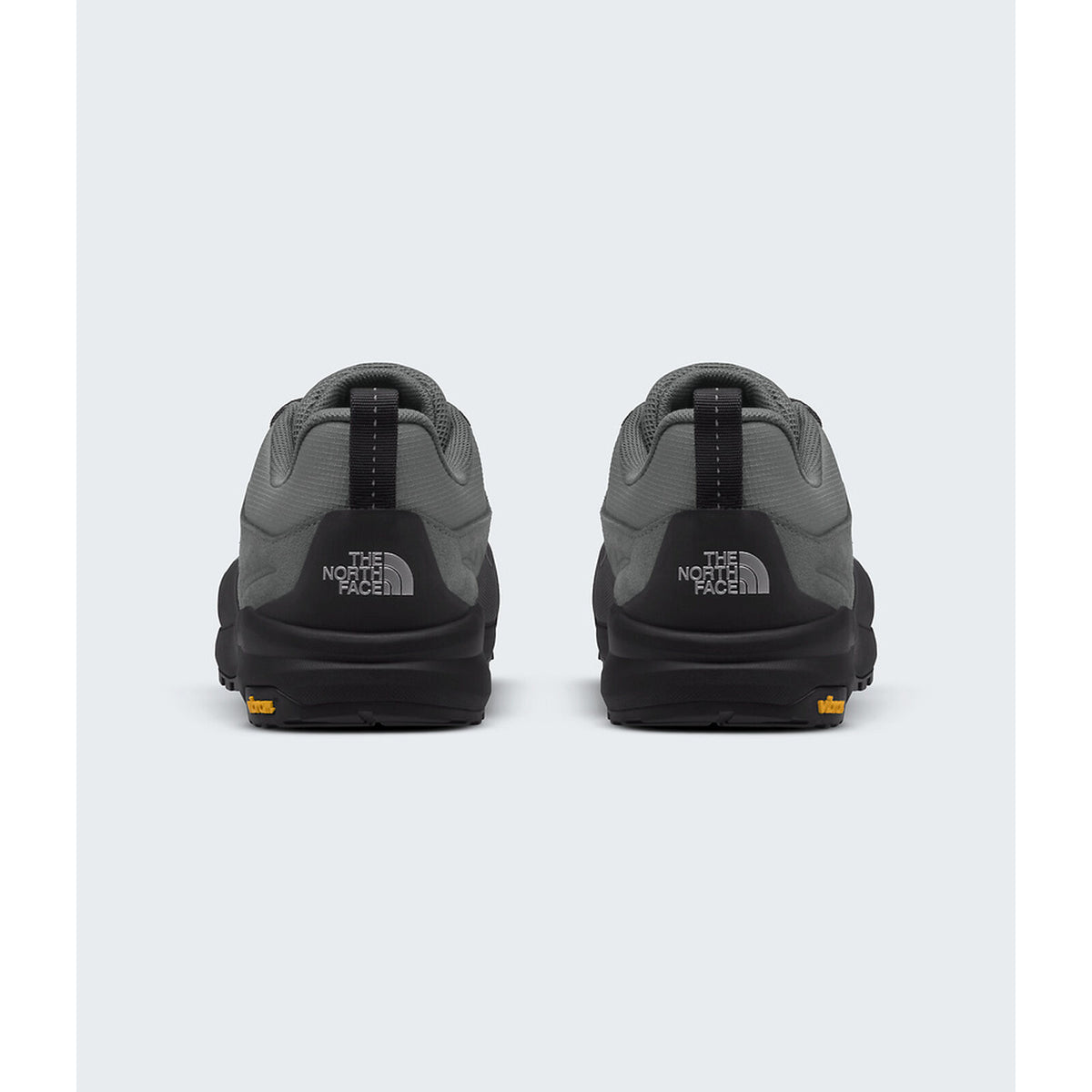 A pair of The North Face low-top sneakers shown from the back, featuring a dark gray and black colorway with a small orange logo accent on the outsole. - The North Face Verto Approach Shoes (Unisex) - Smoked Pearl/TNF Black