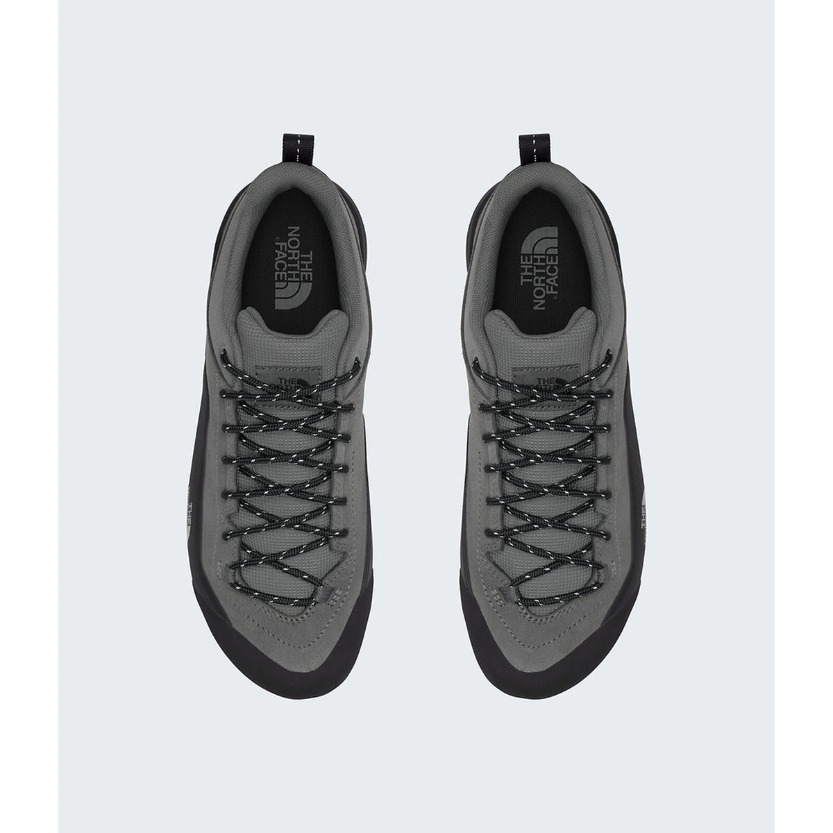 A pair of gray and black low-top sneakers shown from a top-down view on a light gray background. The shoes feature gray suede and mesh uppers with black laces, black soles, and the 'The North Face' logo printed on the tongue. - The North Face Verto Approach Shoes (Unisex) - Smoked Pearl/TNF Black