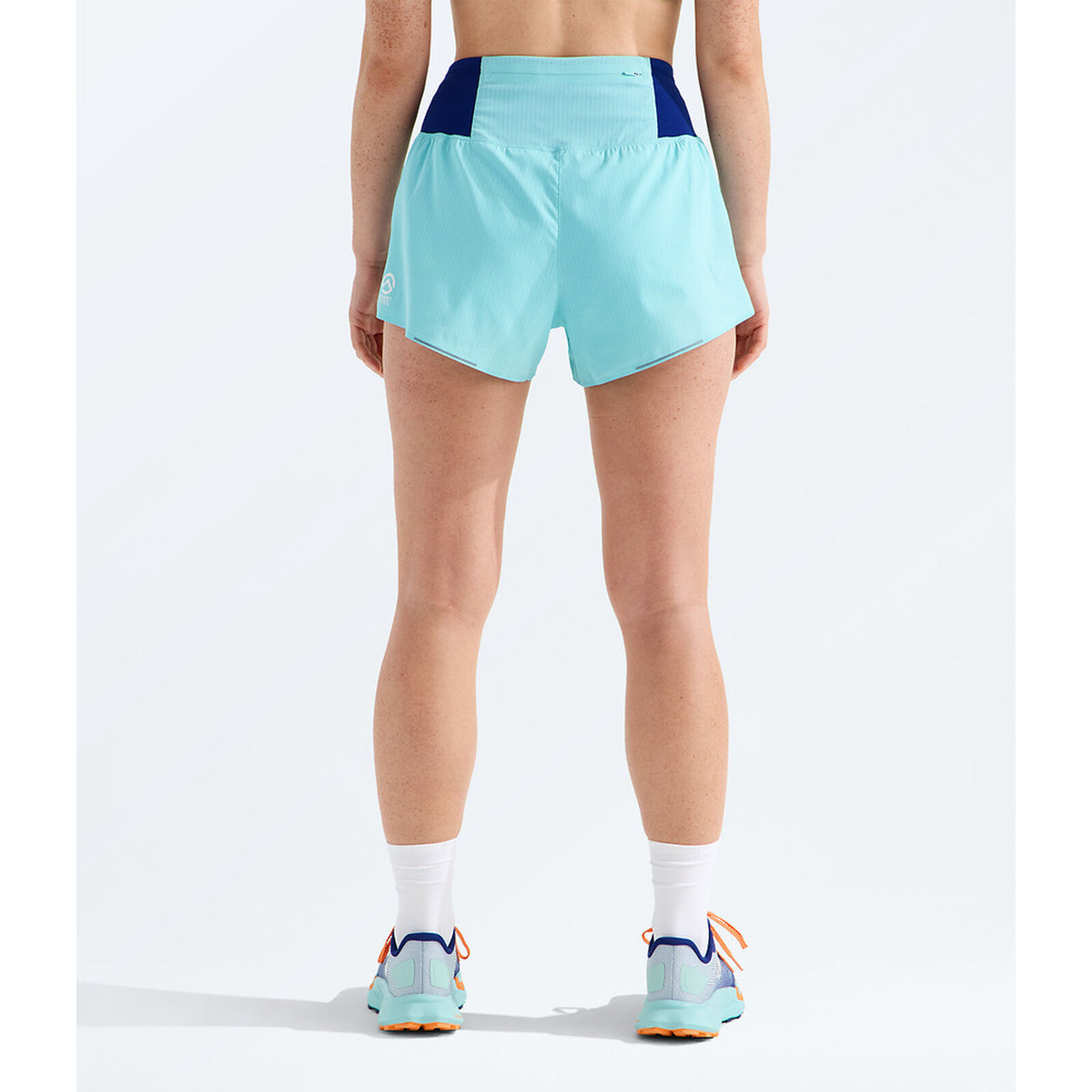 A person shown from the back wearing light aqua athletic shorts with dark navy side panels, white socks, and matching light aqua running shoes against a clean white studio background. - The North Face Summit Pacesetter Short-Graphic (Women's) - Canal Blue