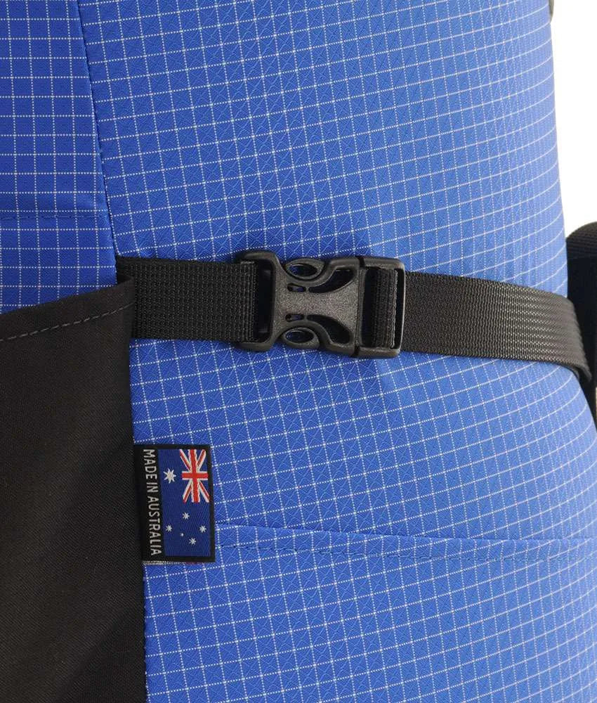 Close-up of a blue grid-patterned life vest with a black webbing strap and quick-release buckle, featuring a black side panel and a small 'Made in Australia' patch with the Australian flag. - One Planet Extrovert 55 Pack - Blue