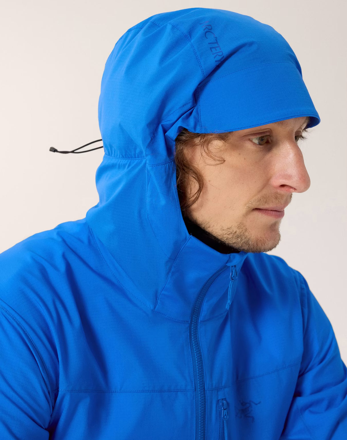 Person wearing a blue hooded jacket against a plain background - Arc'teryx Squamish Hoody (Men's) - Fluidity