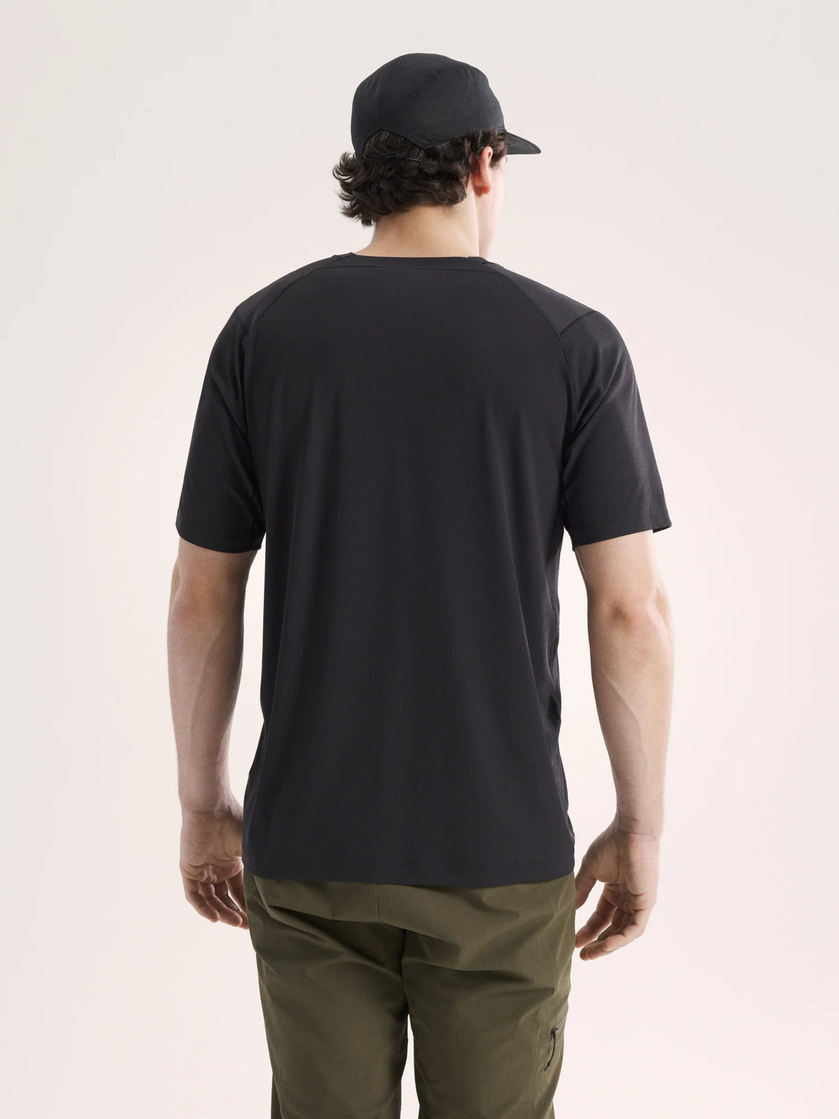Person wearing a black t-shirt and cap from behind on a light pink background - Arc'teryx Cormac Crew Neck Shirt Short Sleeve (Men's) - Black
