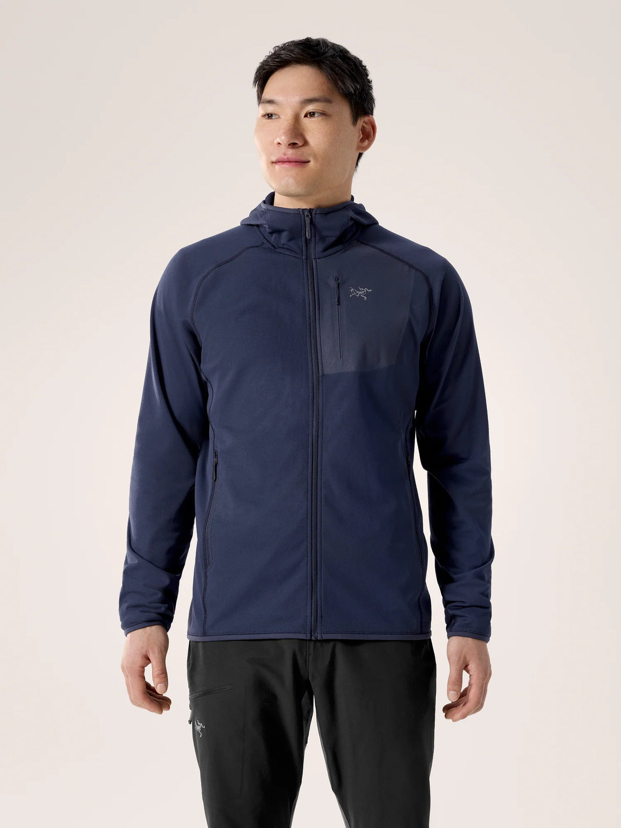 Man wearing a navy blue jacket with a brand logo on a beige background - Arc'teryx Delta Hoody (Men's) - Black Sapphire