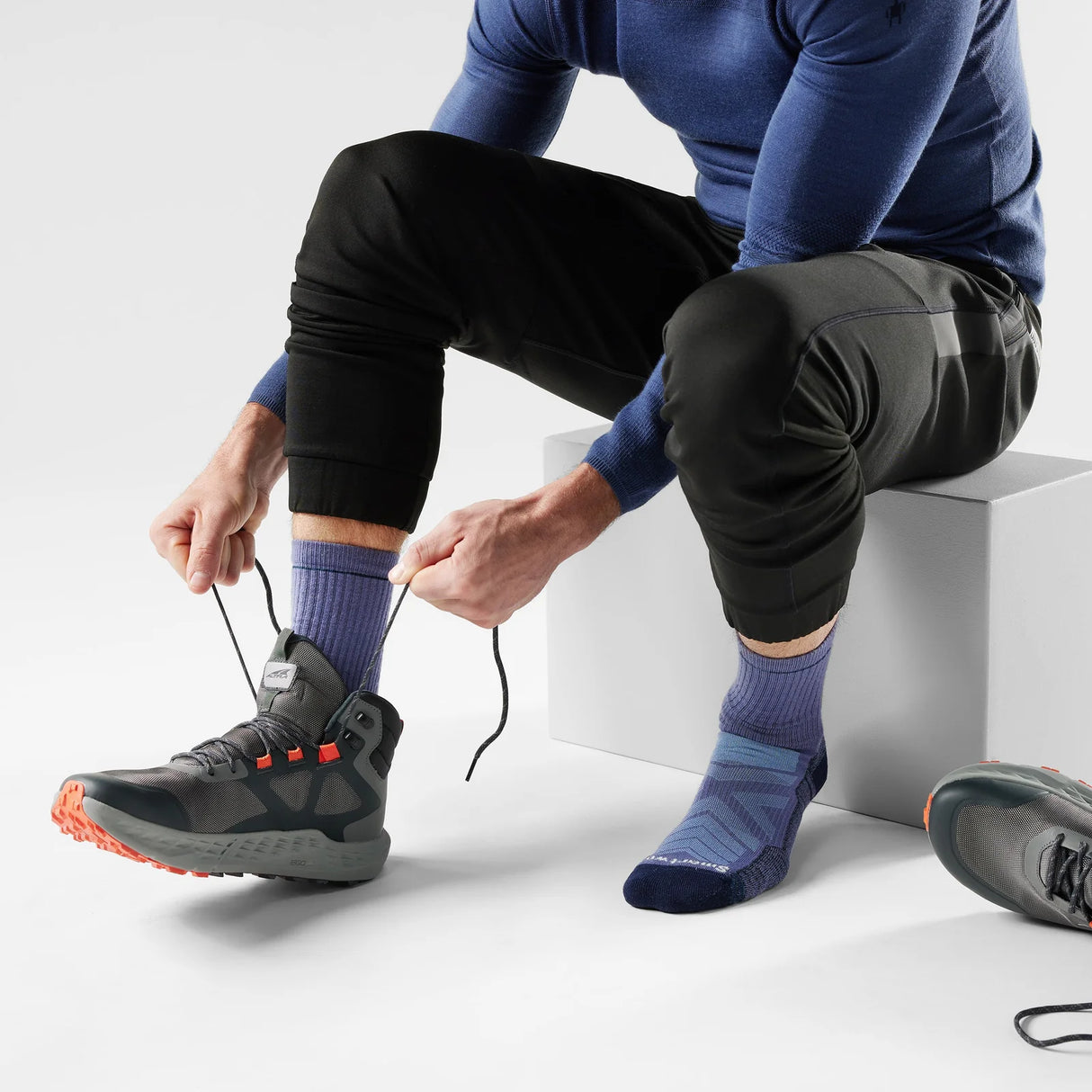 Person tying shoelaces on a black sneaker with a white background - Smartwool Hike Light Cushion Crew Socks (Unisex) - Nightfall Blue