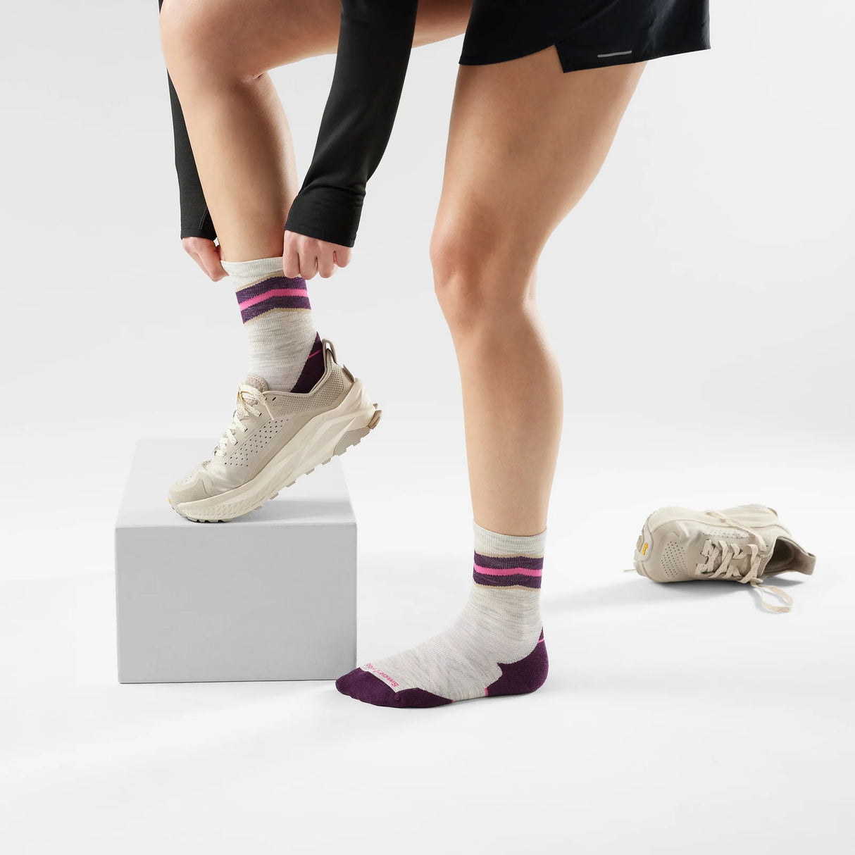 Person wearing white socks with purple accents and white sneakers on a light gray background - Smartwool Run Targeted Cushion Mid Crew Socks (Women's) - Ash