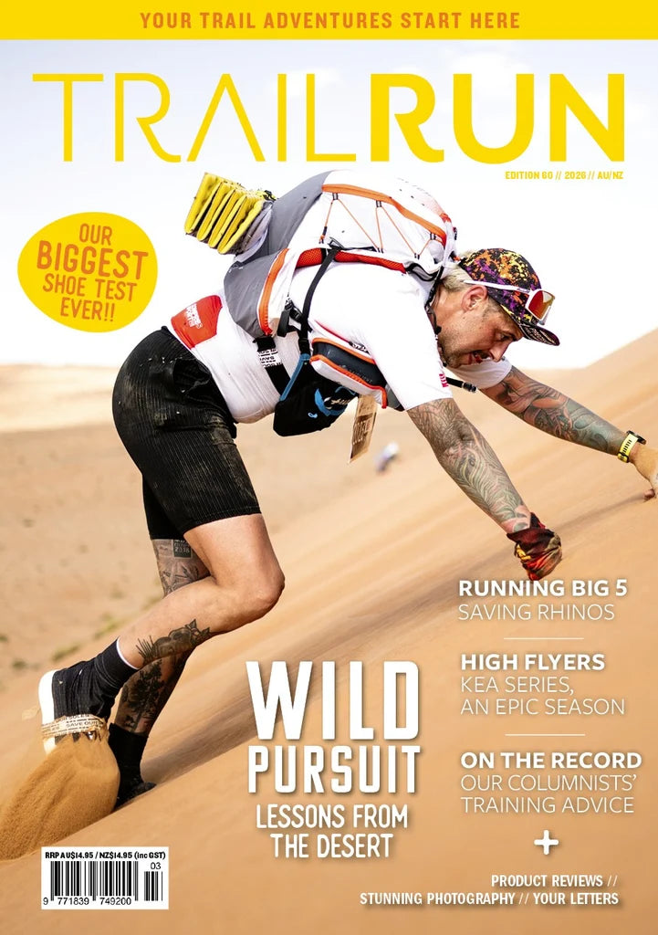 Trail Run magazine cover featuring a mountain biker leaning forward on a sandy dune, with large yellow 'TRAIL RUN' title at the top and cover text including 'WILD PURSUIT' and 'LESSONS FROM THE DESERT'. - Trail Run Magazine - Edition 60 / 2026