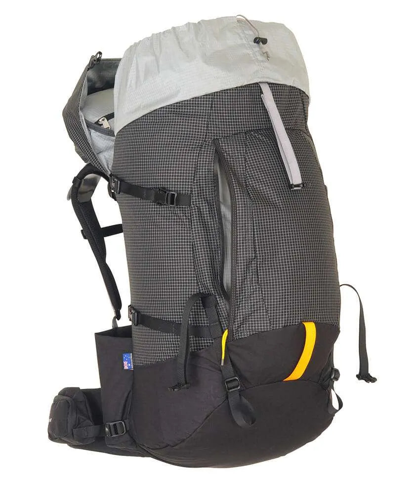 A large technical hiking backpack shown from the side against a plain white background. The backpack features a dark gray and black grid-patterned main body, a light gray top rain cover, black straps and buckles, and a small yellow accent on the lower front pocket. - One Planet Tussock 60L Pack - Black