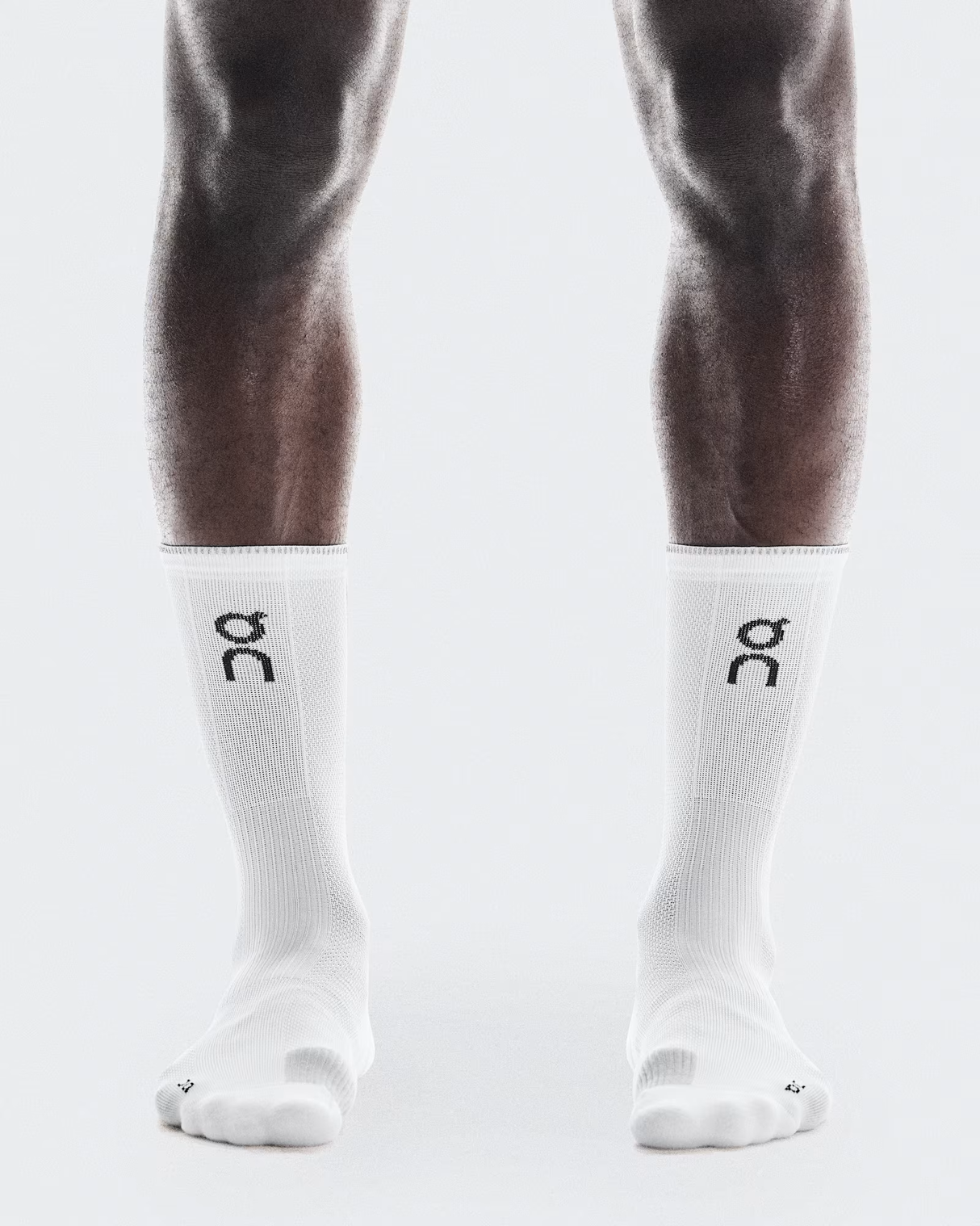 White socks with a logo on the leg worn by a person against a white - On Performance Run Sock High (Unisex) - White/Glacierbackground