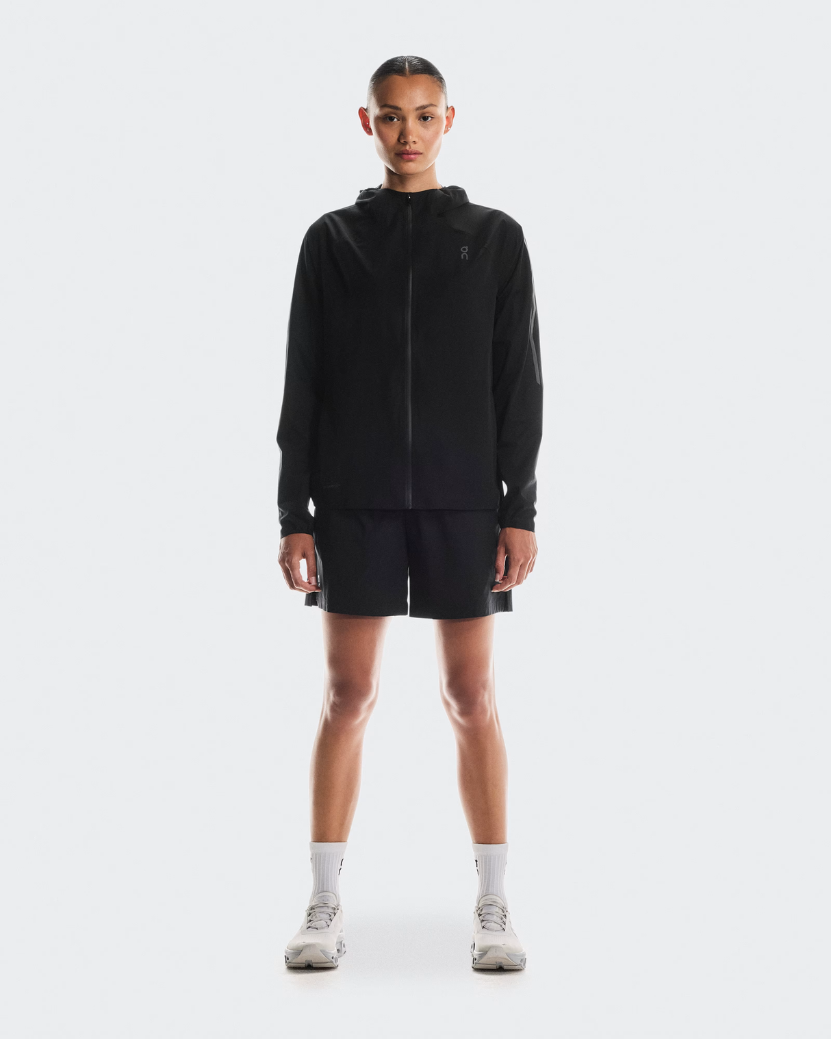 Person wearing a black hoodie and shorts on a white background - On Performance Jacket (Women's) - Black