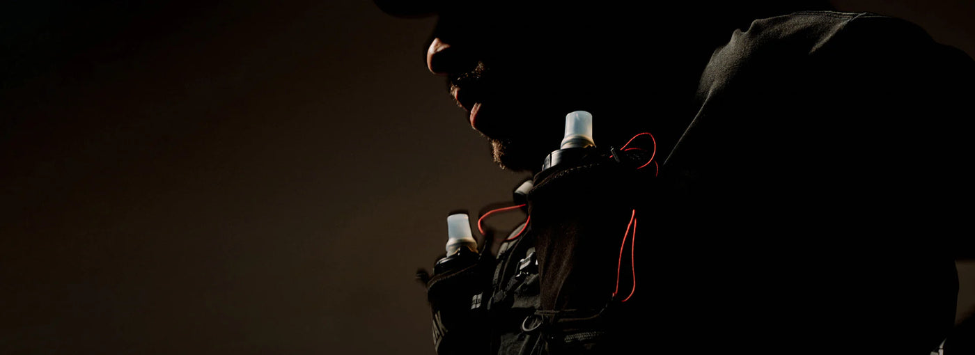 trail runner with a hydration vest from camelbak in front of a dark background