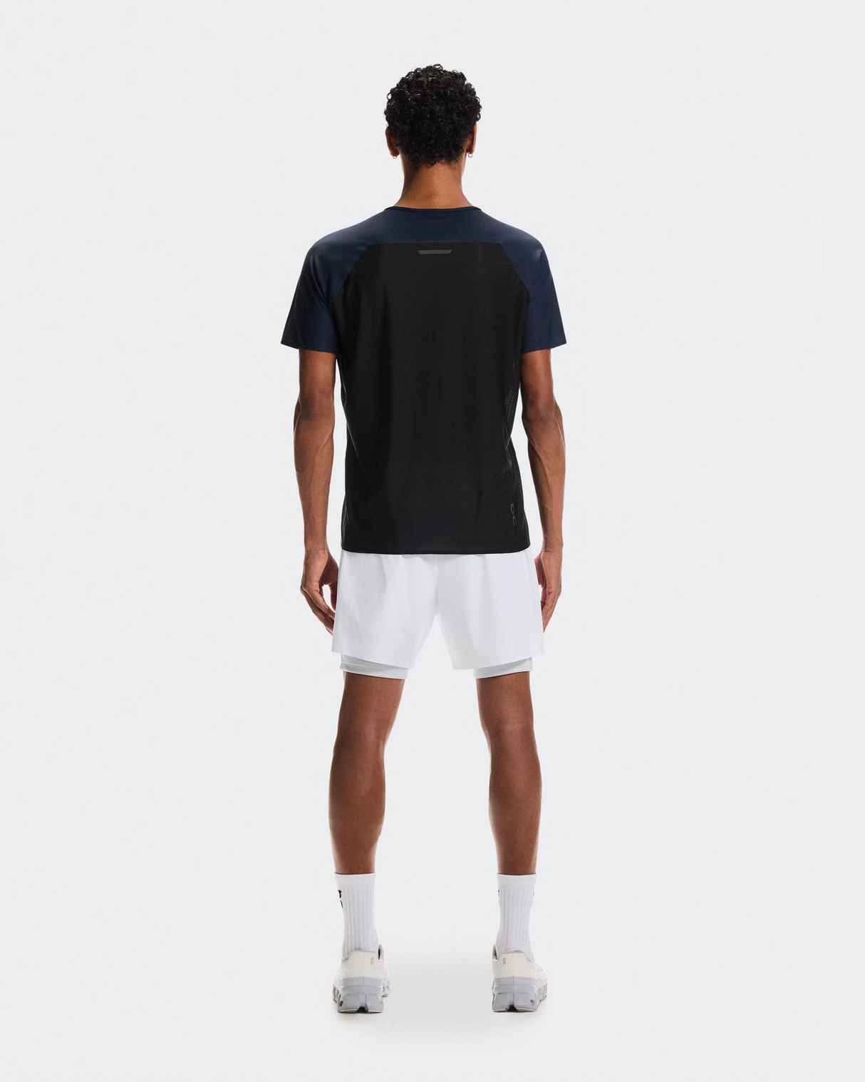 Person wearing a black and navy sports outfit on a white background - On Performance-T (Men's) - Navy/Black