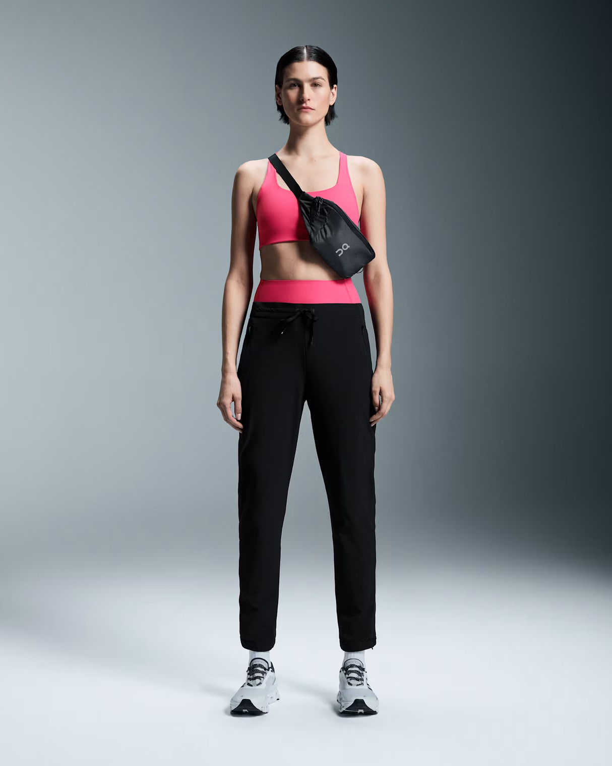 Woman wearing a pink sports bra and black pants with a black bag on a gray background - On Waist Pack 2L Lite - Magnet