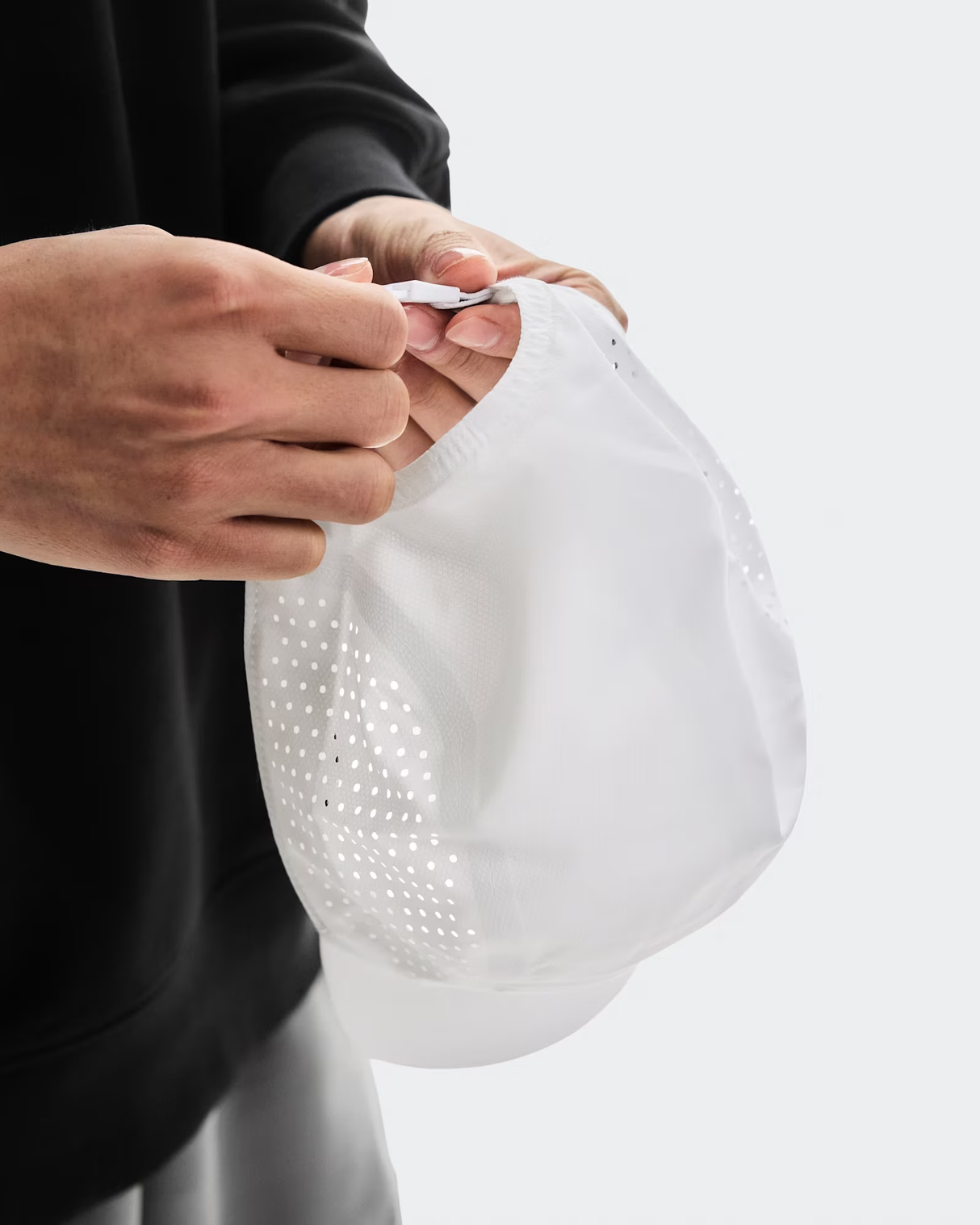 Person holding a white mesh bag with a plain background - On Lightweight Cap - White