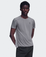 A man wearing a light gray athletic t-shirt with a small dark gray 'on' logo on the left chest, paired with dark gray athletic pants, against a light gray studio background. - On Performance-T (Men's) - Ember/Ore