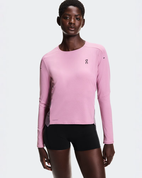 Person wearing a pink long-sleeve athletic shirt and black shorts on a white background - On Performance Long-T (Women's) - Dewberry/Sakura