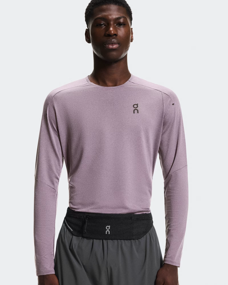 Person wearing a light purple long-sleeve athletic shirt and gray shorts with a brand logo on a white background - On Speed Belt (Unisex) - Black