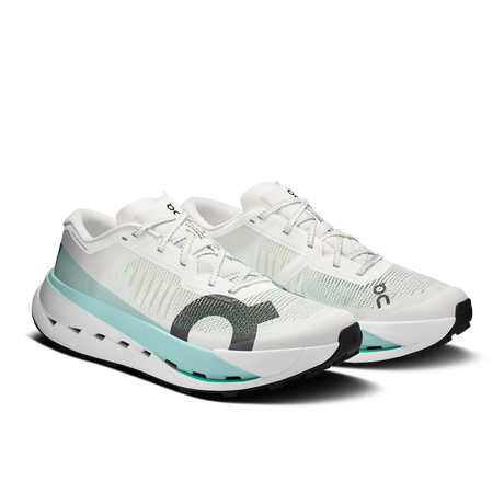 A pair of On running shoes in white and mint green, featuring a textured knit upper, a thick cushioned sole, and the signature On logo on the side, set against a plain white background. - On Cloudultra Pro Shoes (Men's) - Ivory/Celeste
